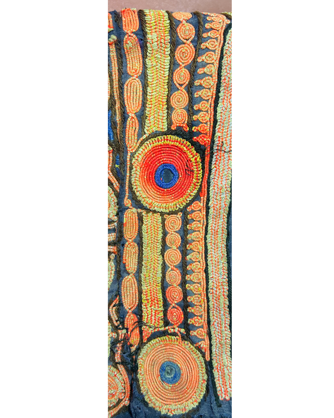 vintage brass cuff bracelet with intricate hand embroidery in bright orange, blue, and green concentric and geometric patterns.