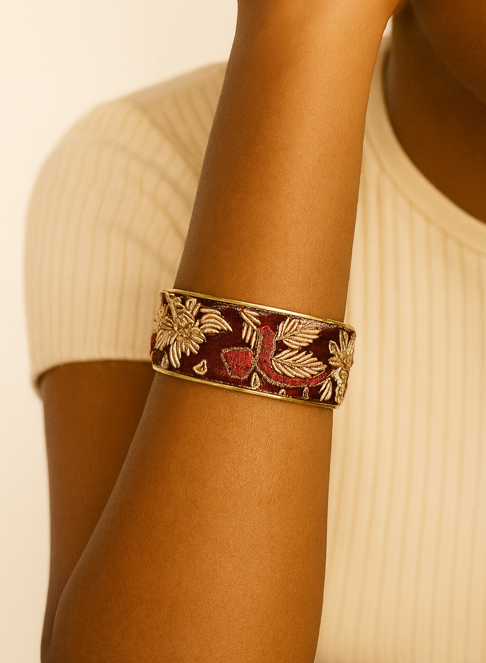 Close-up of a model wearing the Guinevere 1-Inch cuff bracelet, featuring a deep burgundy textile embroidered with gold floral motifs and leaves set into a slim brass cuff, highlighting the refined detail and handcrafted jewelry texture, handcrafted in Shreveport, LA by Redd Dott Jewelry.