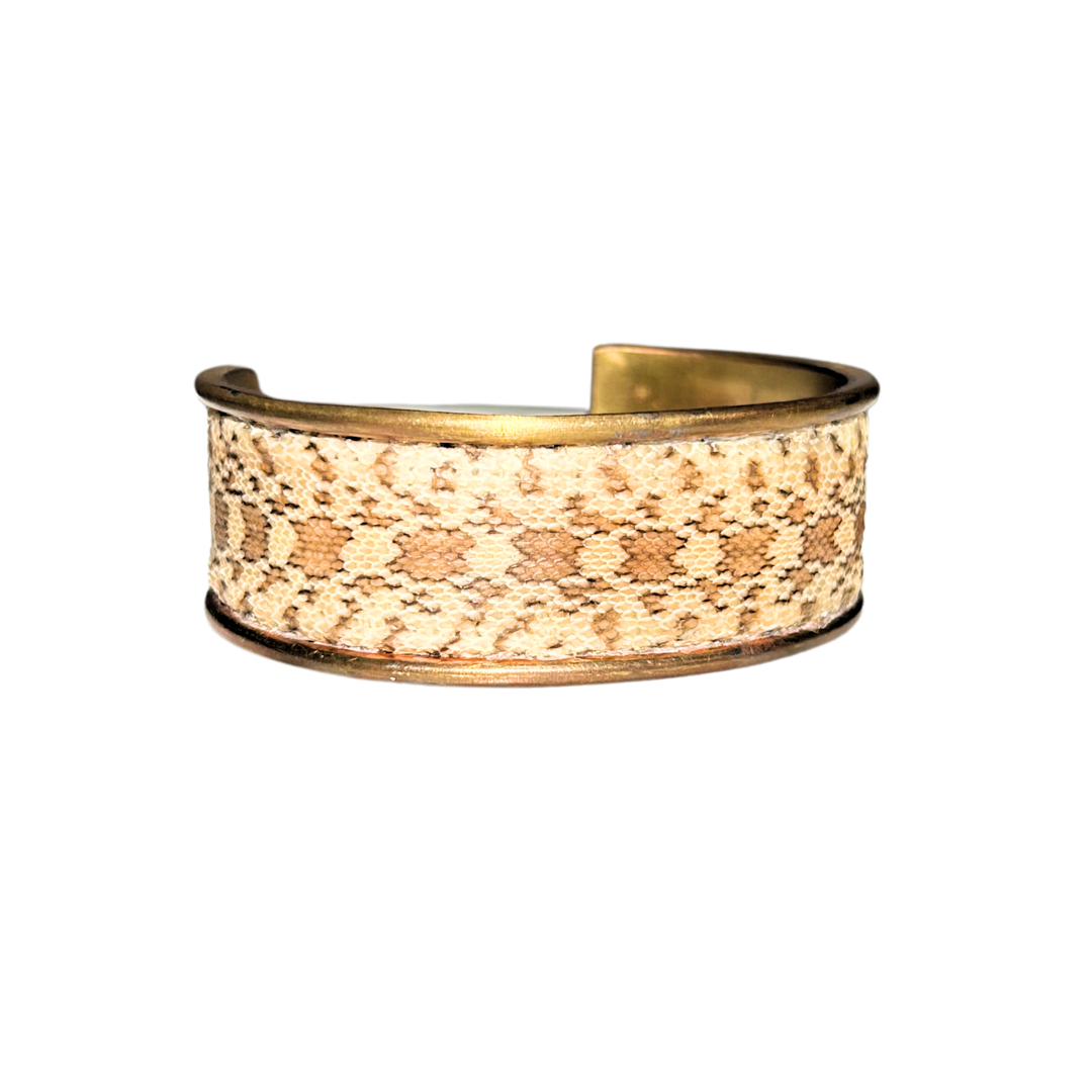 A handcrafted nature inspired jewelry cuff bracelet by Redd Dott Jewelry, featuring genuine gopher snake skin in sandy, caramel tones set in a warm brass frame. Bold, earthy, and rich in texture.