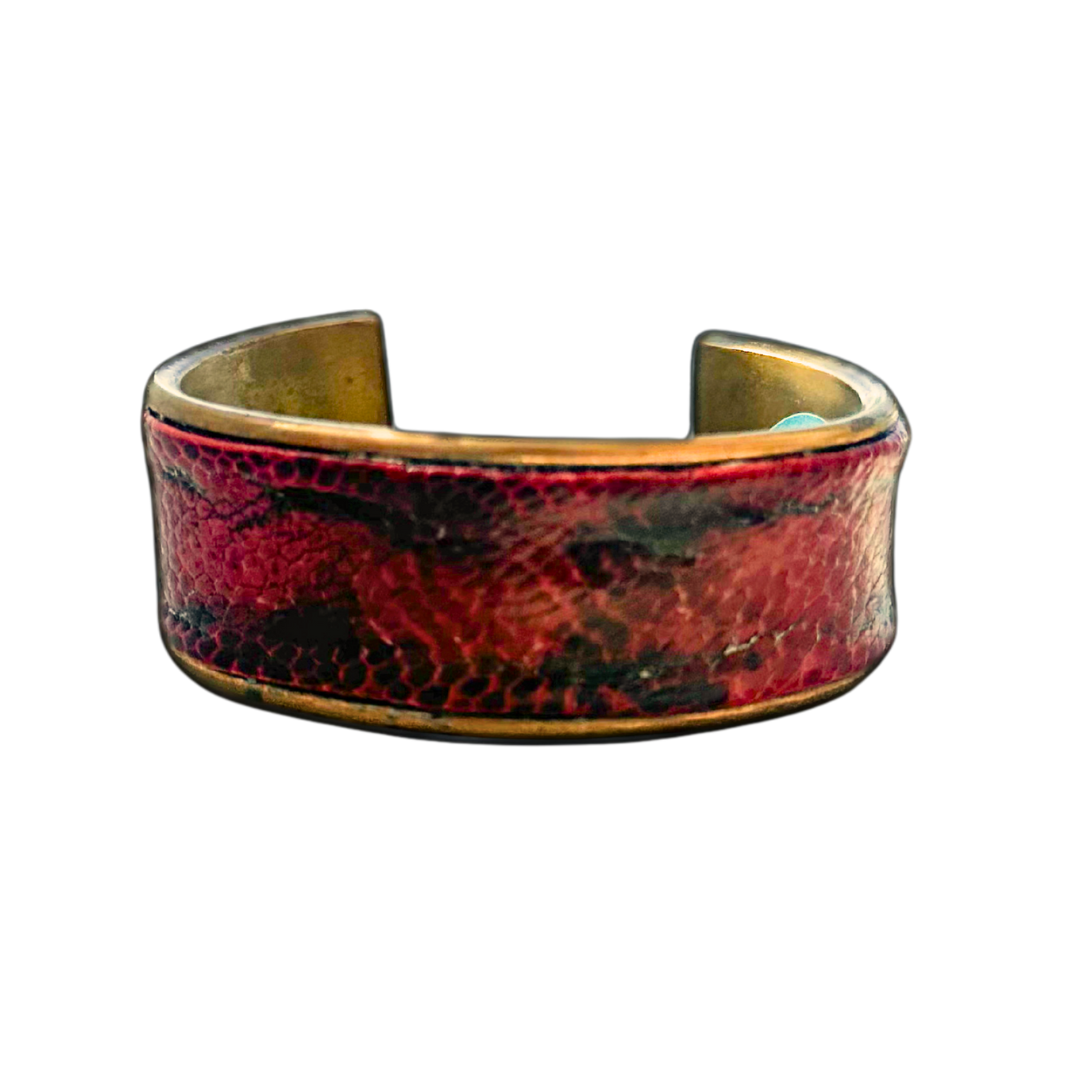 1-inch gold cuff bracelet wrapped in genuine ostrich thigh leather with deep burnished red and black tones, featuring textured dimples and brass interior; handcrafted statement jewelry by Redd Dott.