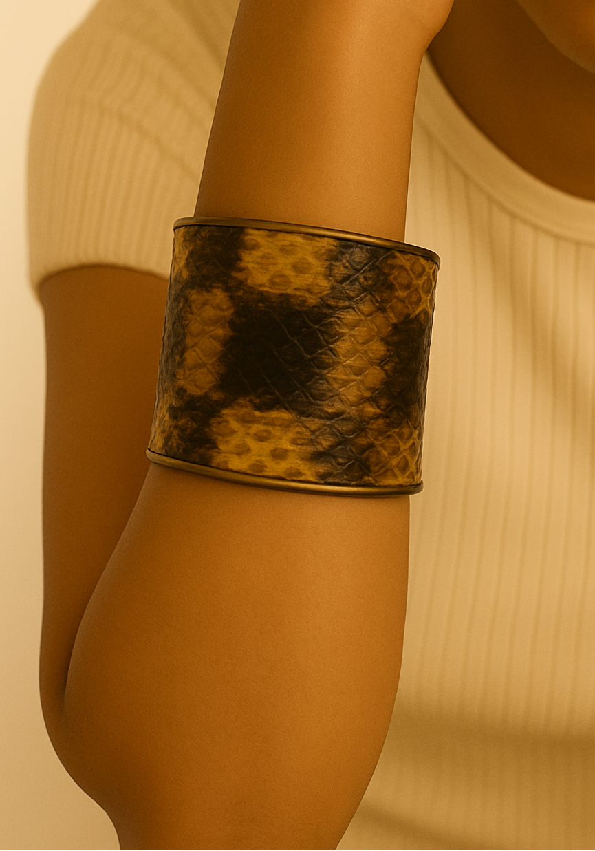 Close-up of a model wearing a 2-Inch genuine bull snake skin cuff bracelet by Redd Dott Jewelry, featuring rich brown and golden tones with natural scale pattern wrapped around a wide brass cuff, highlighting the bold texture and handcrafted jewelry detail, handcrafted in Shreveport, LA by Redd Dott Jewelry.