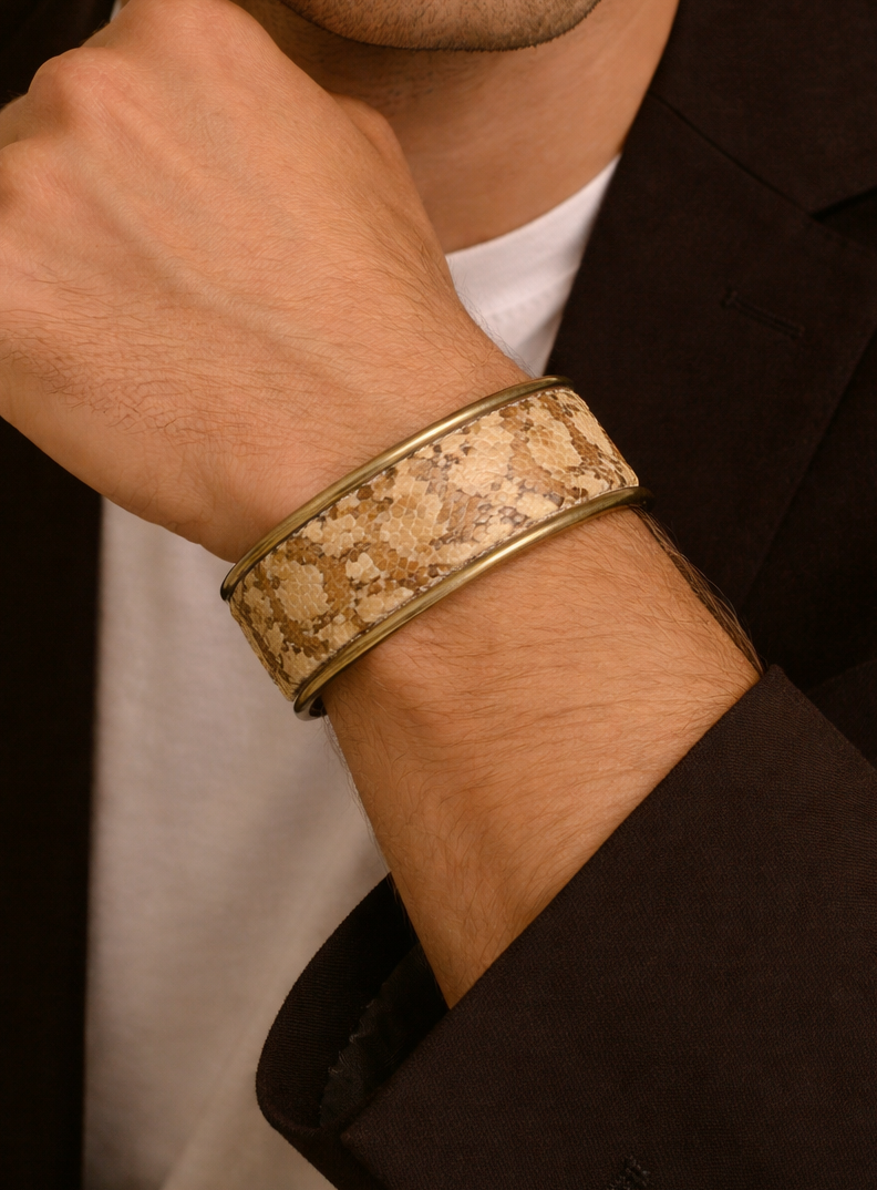 Close-up of a model wearing the men’s 1-Inch gopher snake skin cuff bracelet by Redd Dott Jewelry, featuring warm tan and sandy beige scale pattern with natural texture set into a slim brass cuff, highlighting the organic surface and handcrafted cuff bracelet detail, handcrafted in Shreveport, LA by Redd Dott Jewelry.