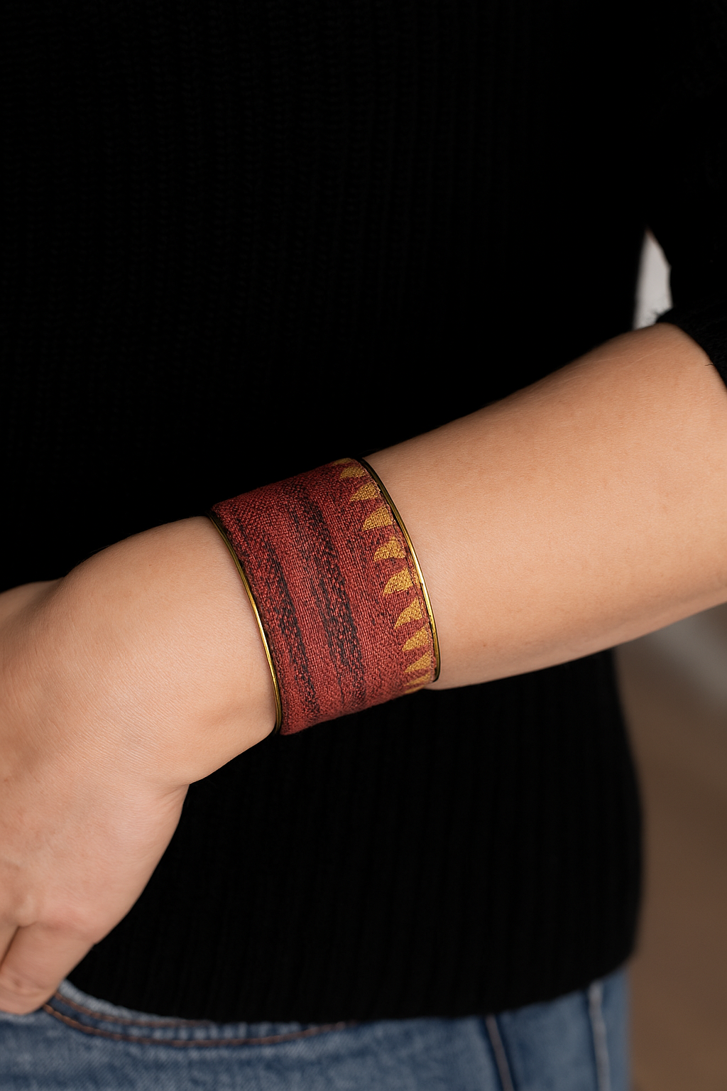 A 3-inch brass cuff bracelet wrapped in deep ruby-red woven fabric with subtle tonal stripes, shown on the wearer’s wrist against a neutral background.