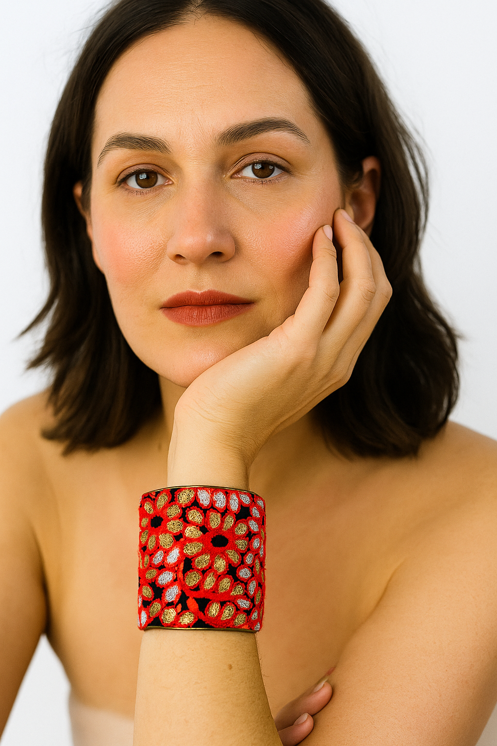 A 3-inch brass cuff bracelet wrapped in black fabric with coral, gold, and silver embroidered petals, shown on the wearer’s wrist against a neutral backdrop.