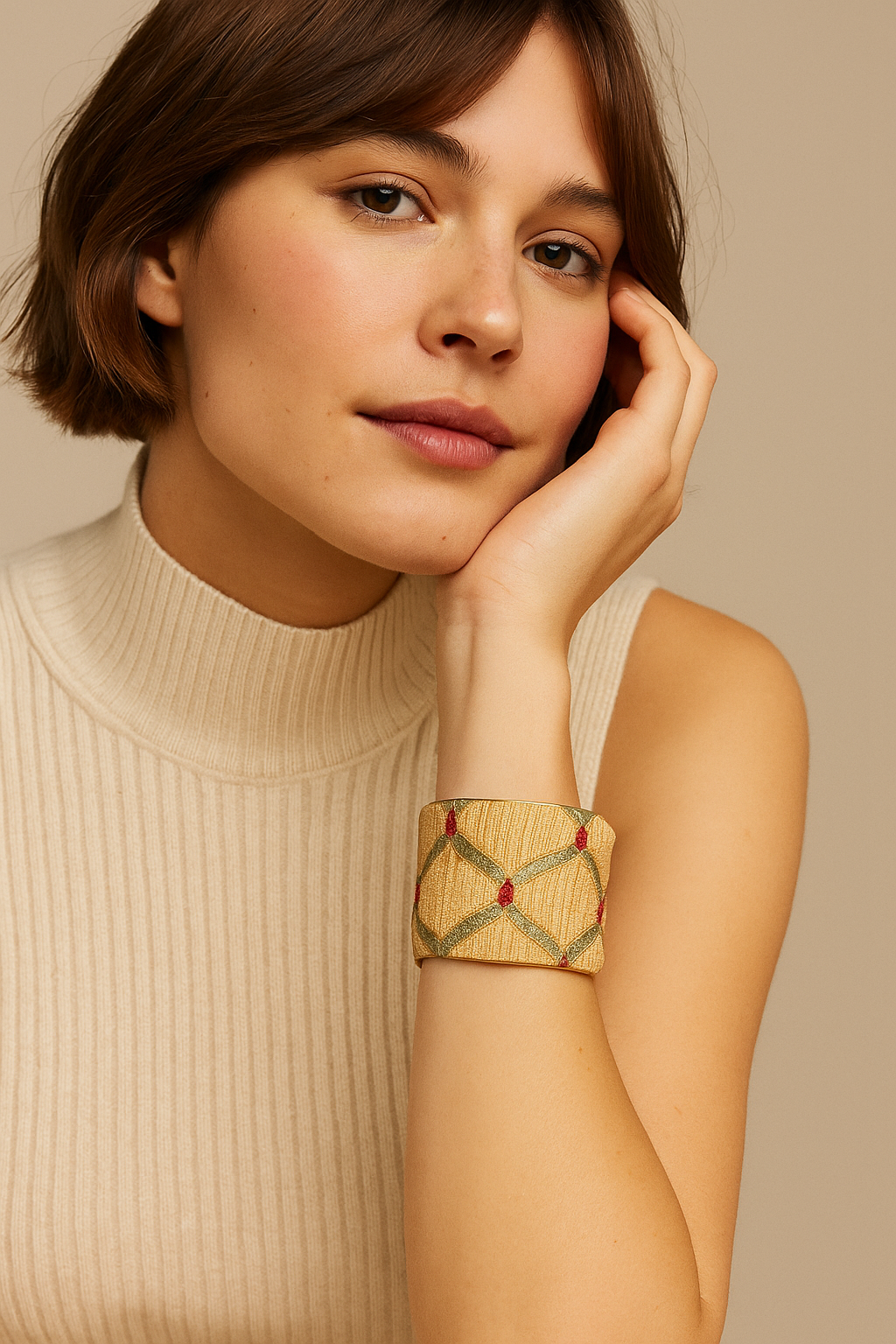 A 2-inch brass cuff bracelet wrapped in yellow jacquard with a hand-embroidered sage lattice and scarlet accents, shown on the wearer’s wrist against a neutral backdrop.