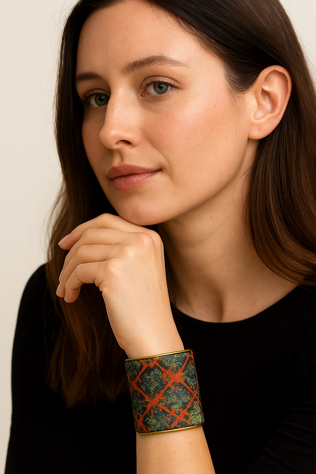 A 3-inch brass cuff bracelet wrapped in navy jacquard with a metallic terracotta lattice overlay, shown on the wearer’s wrist against a black top and neutral background.