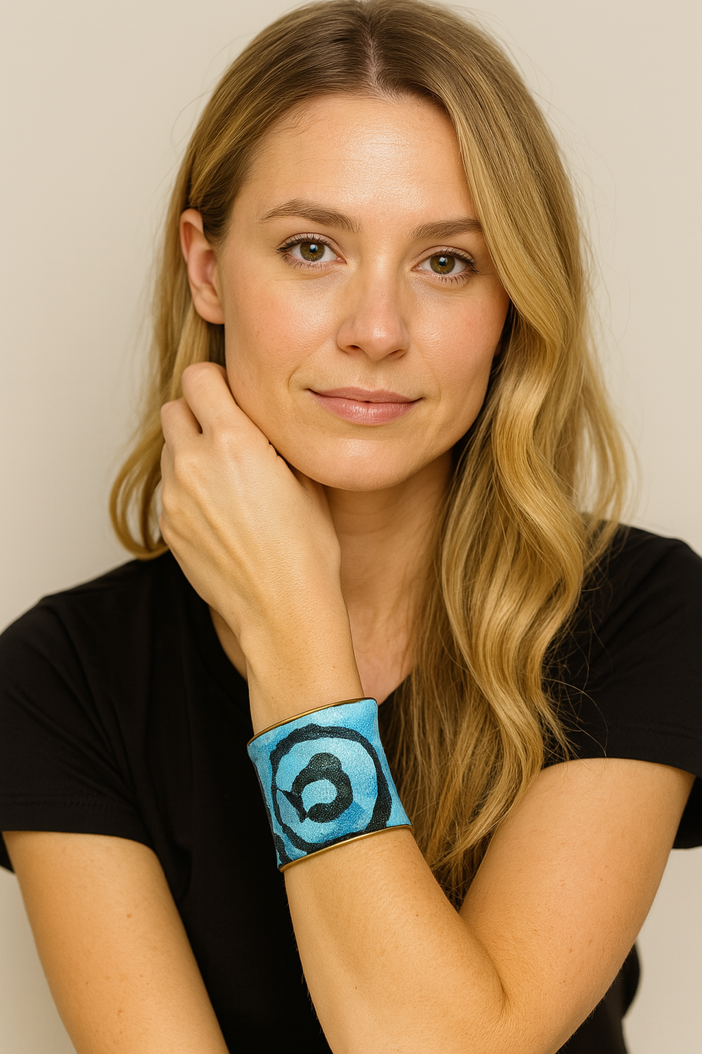A 3-inch brass cuff bracelet wrapped in canvas painted with aqua gradient and navy swirl, shown on the wearer’s wrist against a black top and neutral background.