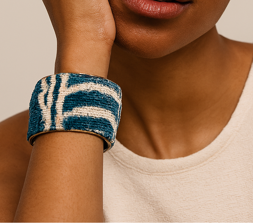Close-up of a woman’s wrist wearing the Kenji 2-Inch cuff bracelet, featuring a textured teal and ivory woven pattern wrapped around a brass cuff,  a tactile handcrafted jewelry look, handcrafted in Shreveport, LA by Redd Dott Jewelry