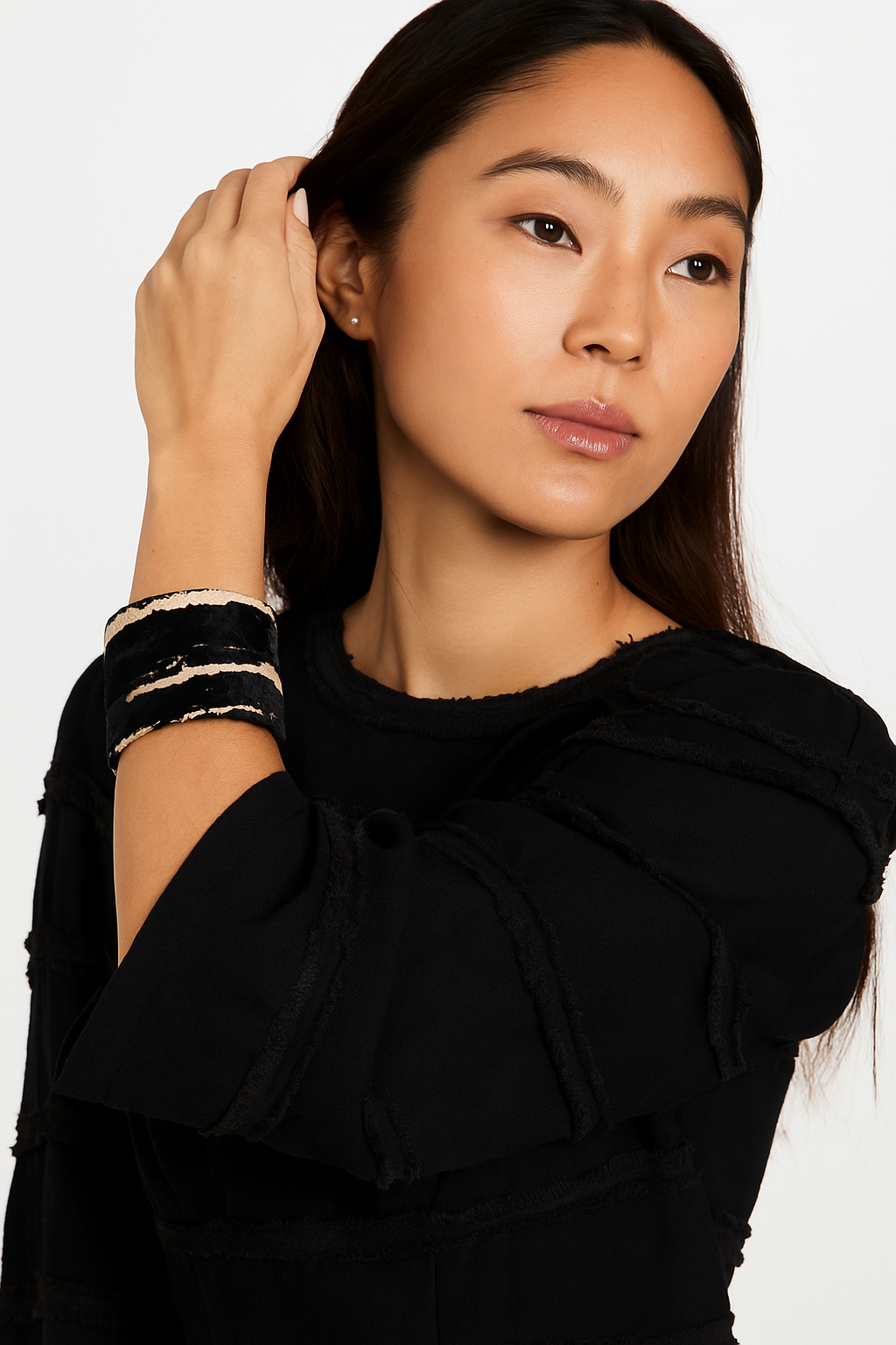 Female model in a black top wearing a 3-inch wide brass cuff bracelet wrapped in black velvet with cream stripe accents on her left wrist. A bold, one of a kind jewelry statement among cuff bracelets for women.
