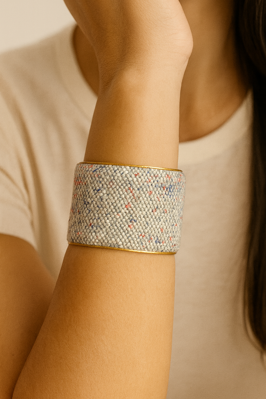 Close-up of a model wearing the Brielle 2-Inch cuff bracelet, featuring a soft ivory woven textile with subtle flecks of blue and rust framed by a warm brass edge, highlighting this wide cuff bracelet’s understated texture and handcrafted finish, handcrafted in Shreveport, LA by Redd Dott Jewelry.