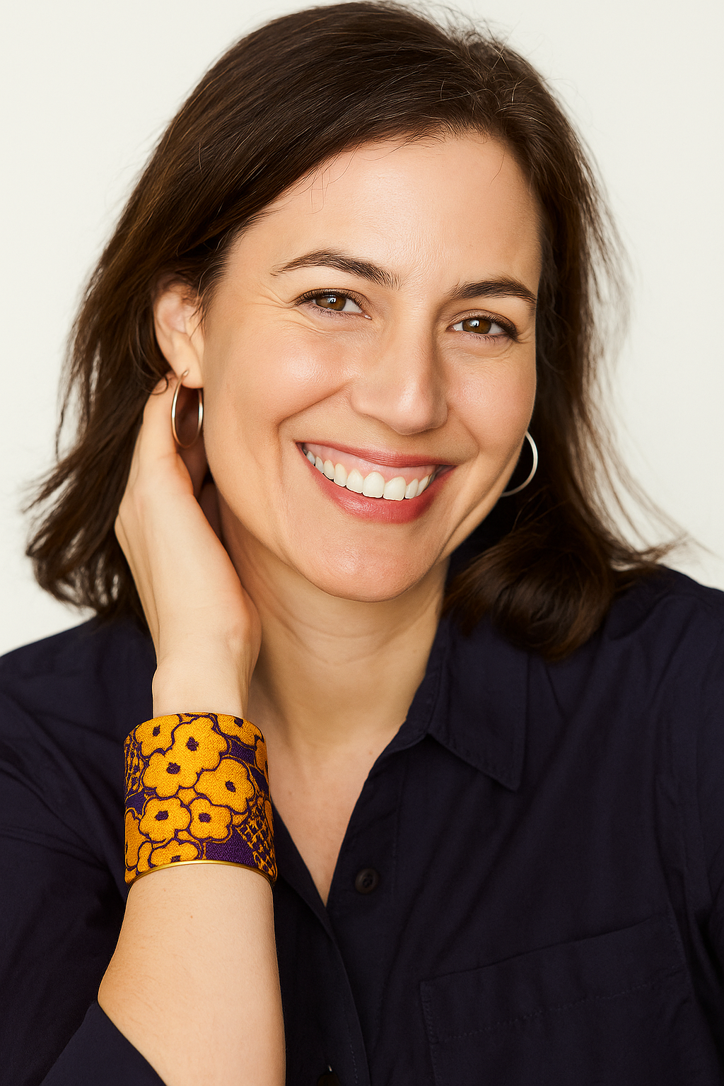 A female model’s wrist adorned with a 3-inch raw brass cuff bracelet featuring gold and purple team-color floral-print fabric—an eye-catching one of a kind jewelry statement among cuff bracelets for women.