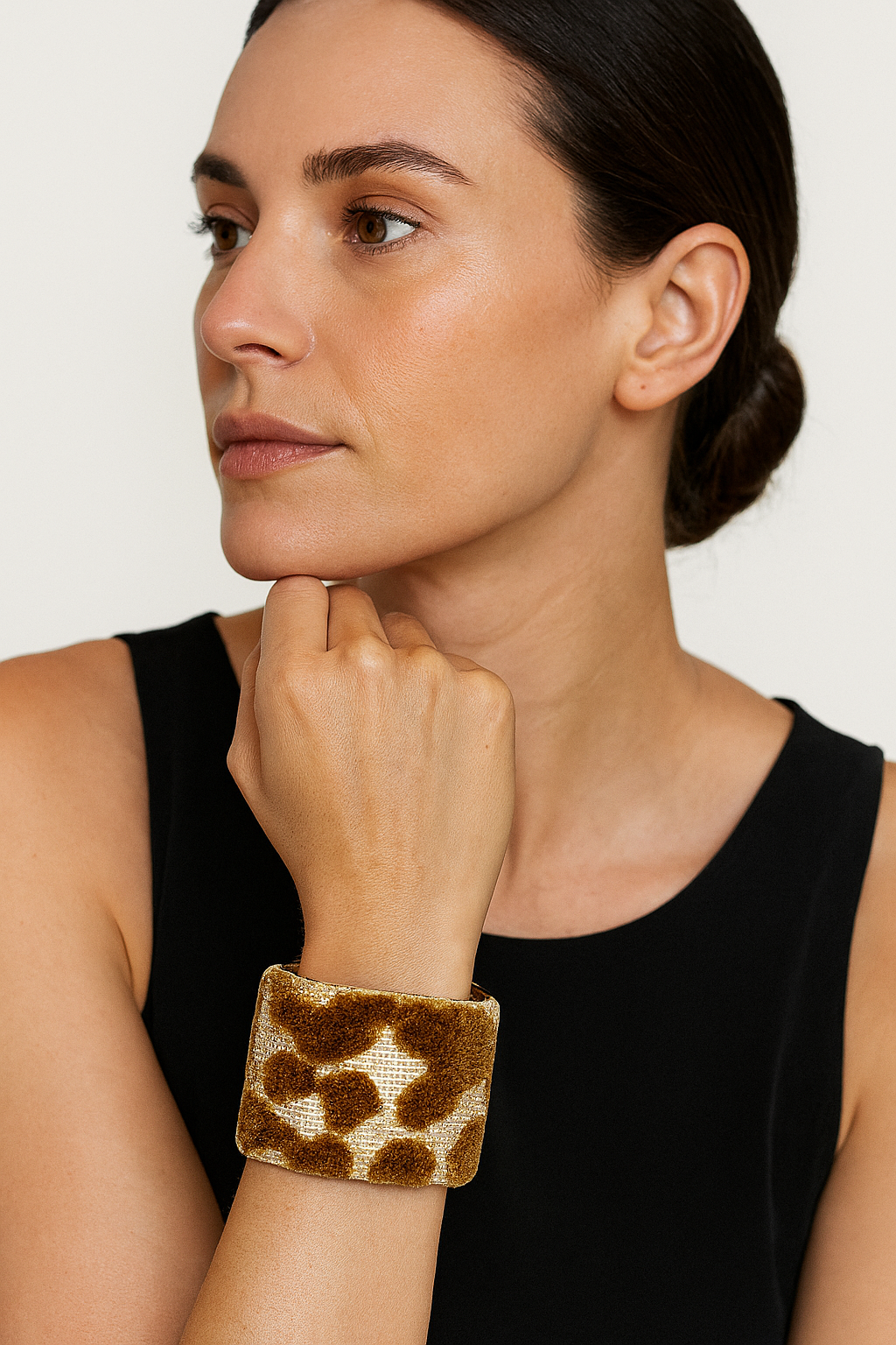 A female model’s wrist adorned with a 2-inch raw brass cuff bracelet featuring soft brown flocked circles on an ivory background—an elegant one of a kind jewelry statement in cuff bracelets for women.