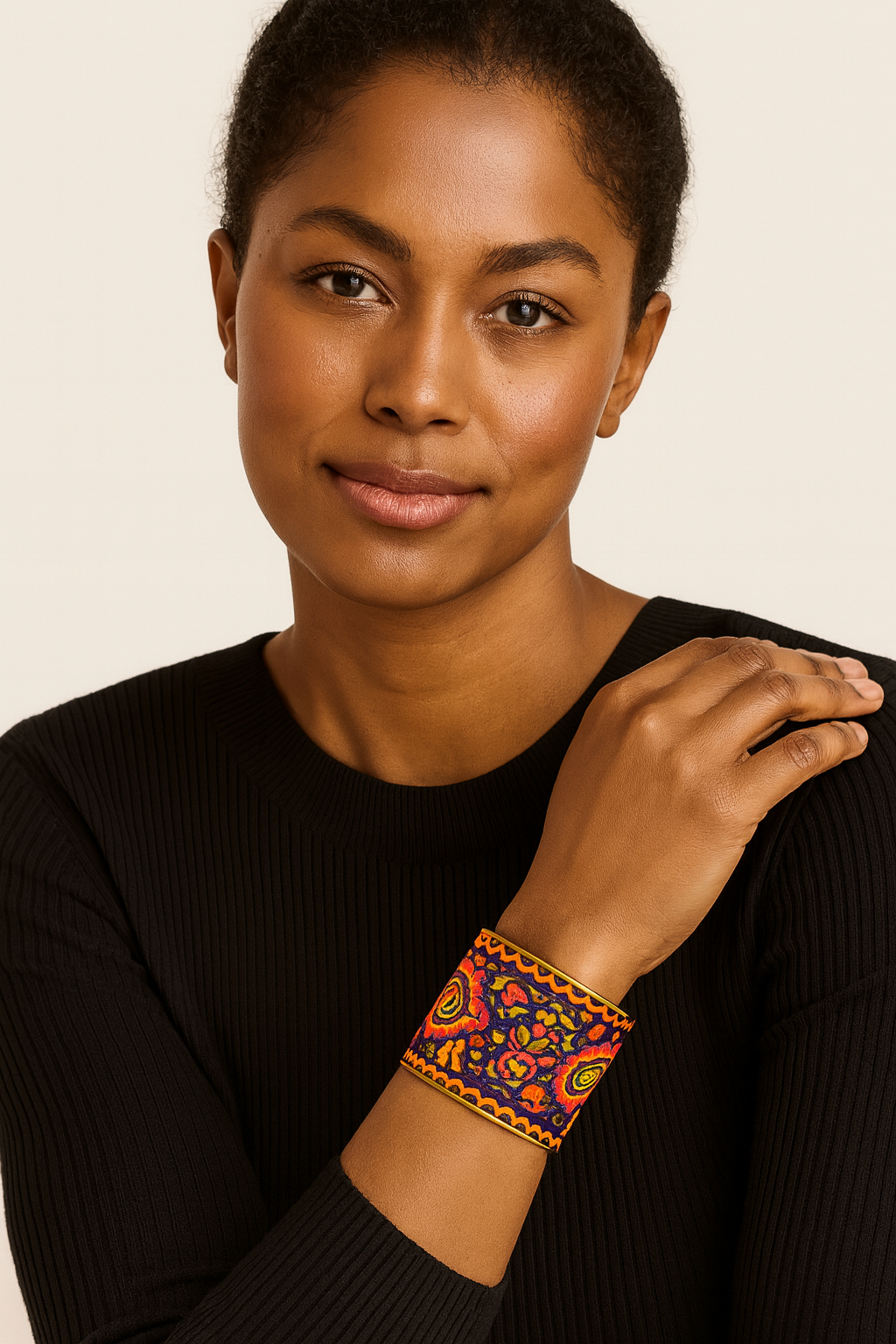 Model wearing the Redd Dott Madison 3-inch cuff bracelet featuring a bold multicolor embroidered design in red, yellow, and navy with intricate patterns, creating a vibrant statement accessory against a black top.