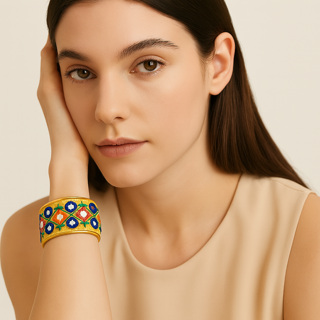 Redd Dott Maeva 1-inch cuff bracelet with a golden base, embroidered in a diamond motif featuring navy blue, orange, and green floral-inspired patterns, framed in brass.