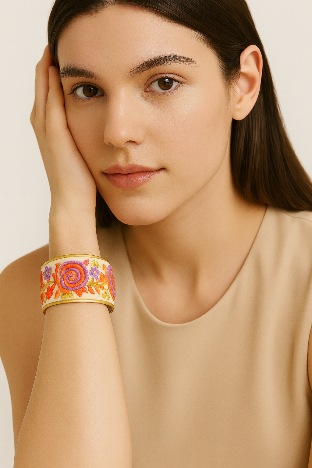 Redd Dott Marcia 1-inch cuff bracelet featuring vibrant embroidered spirals in orange and purple with floral accents on a soft cream background, framed in brass, blending playful charm with artisanal elegance.