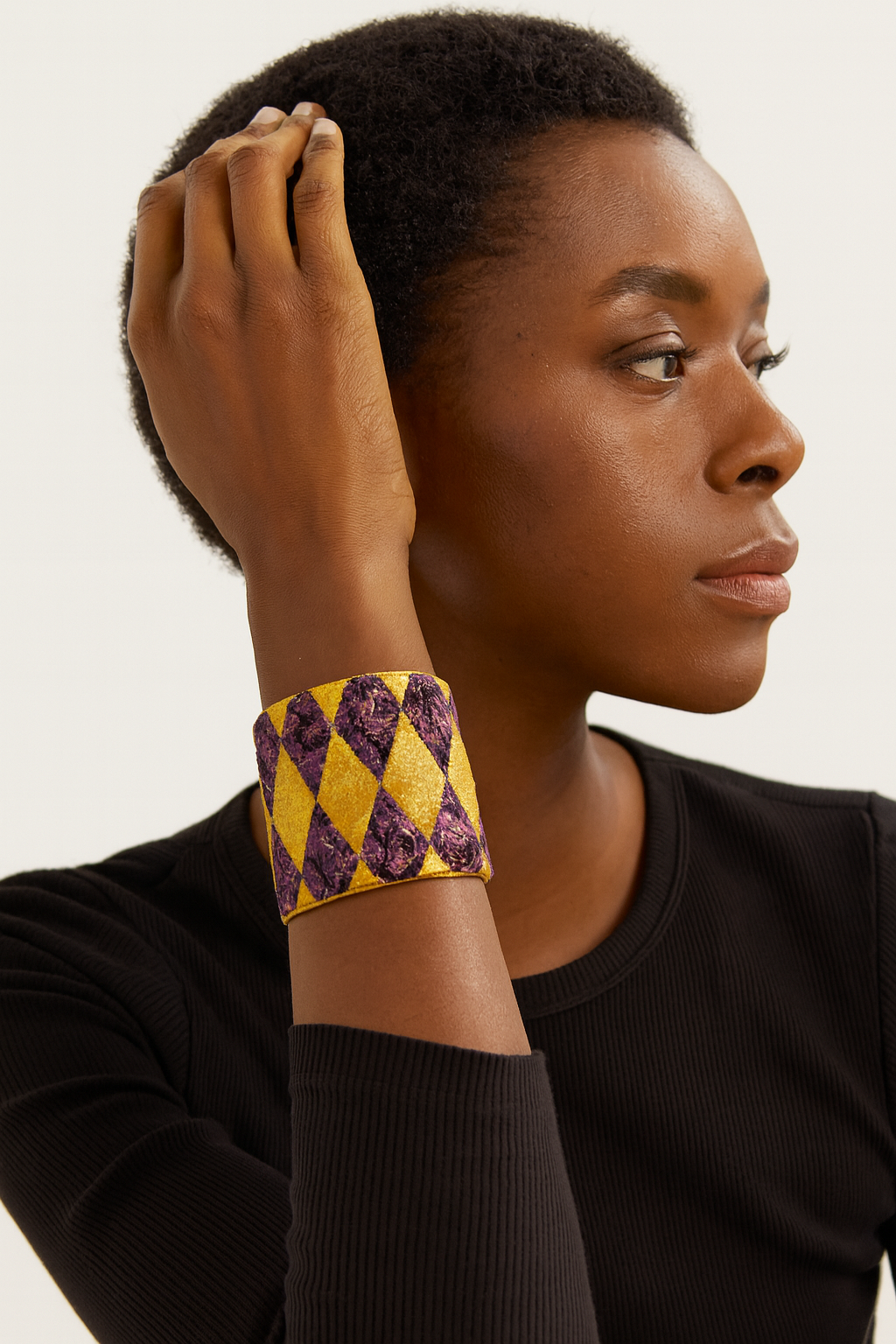 Side view of the Redd Dott Mardi Vibes Only 3-inch cuff bracelet, featuring a bold purple and gold harlequin diamond pattern with textured detailing, framed in brass for a festive Mardi Gras–inspired statement.
