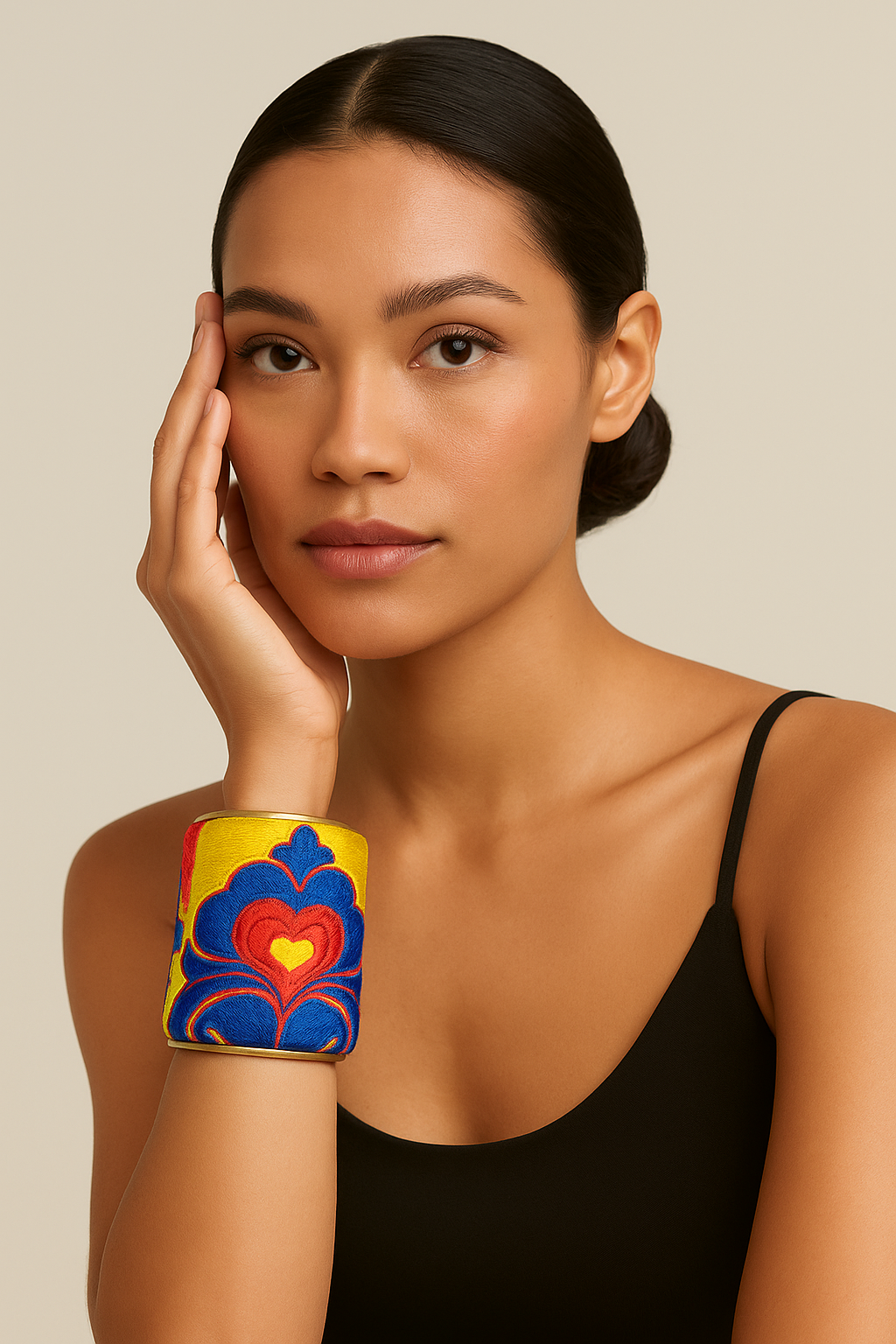 Model wearing the Redd Dott Marigold 3-inch cuff bracelet, featuring bold embroidery in yellow, red, and blue with a striking heart-inspired motif, framed in polished brass for a vibrant, artistic statement.