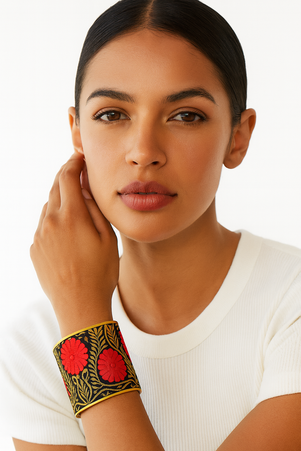 Model wearing the Redd Dott Marinette 3-inch cuff bracelet, showcasing bold red embroidered flowers with golden leaves on a black background, framed in polished brass for a striking statement look.