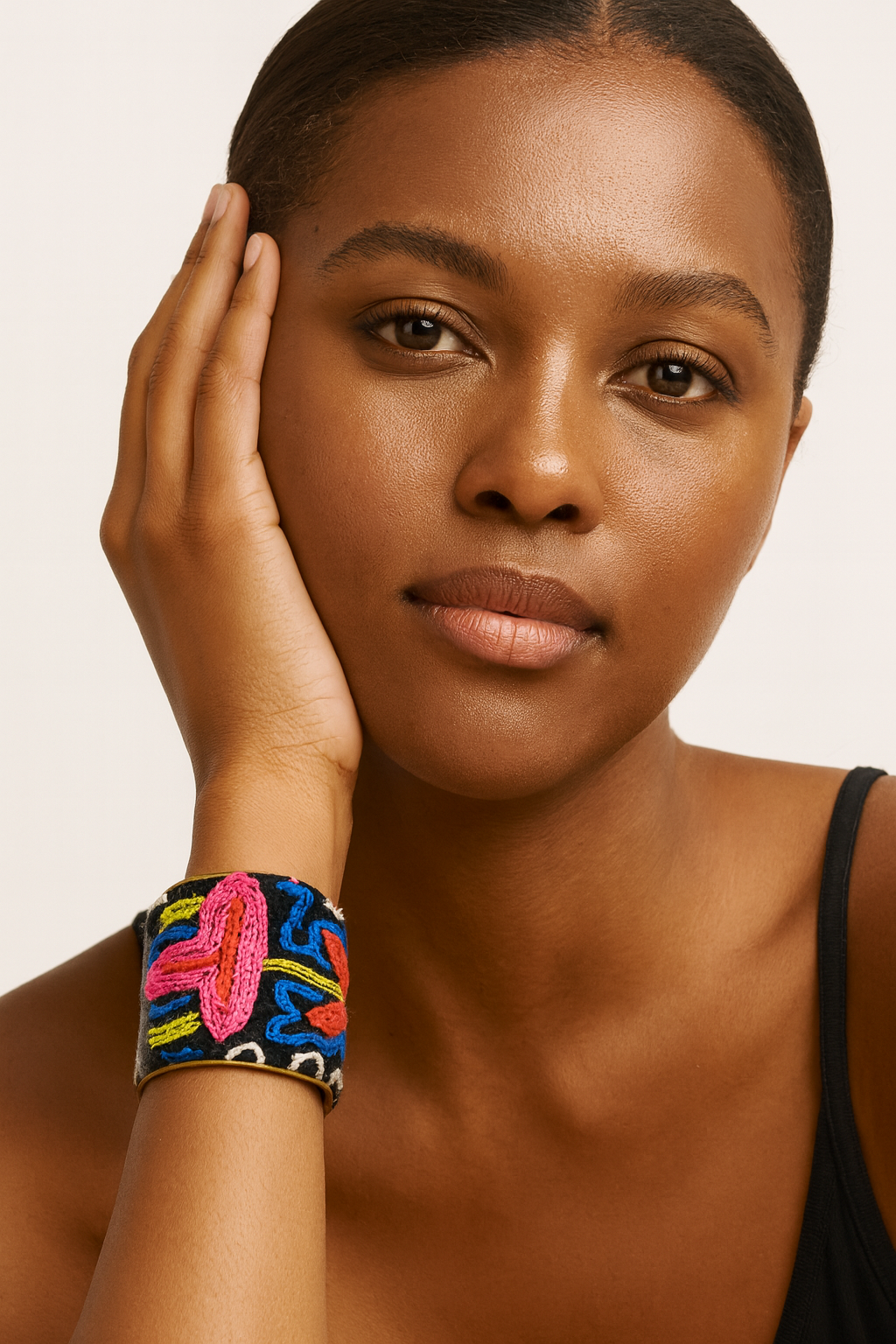 Model wearing the Redd Dott Marlowe 3-inch cuff bracelet, hand-embroidered with bold pink, orange, and blue florals on a black base, framed in gold for a striking statement piece full of artistry and vibrance.