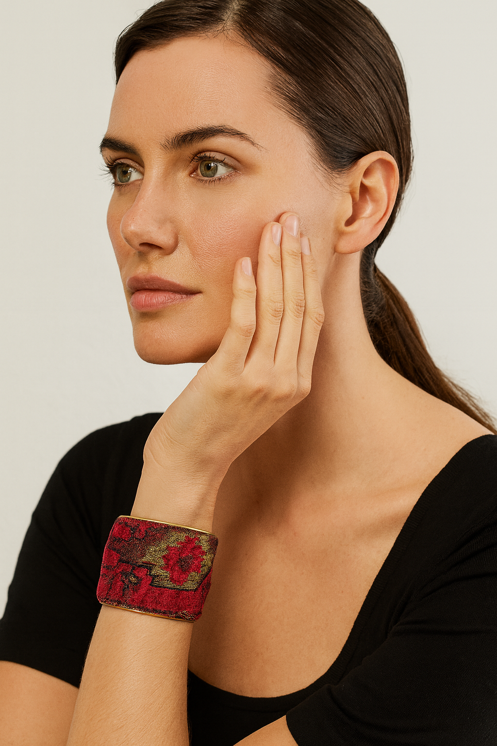 Model wearing the Redd Dott Maxine 2-inch cuff bracelet, featuring rich red and deep green tapestry-style embroidery with a distressed vintage pattern, framed in a gold cuff base.