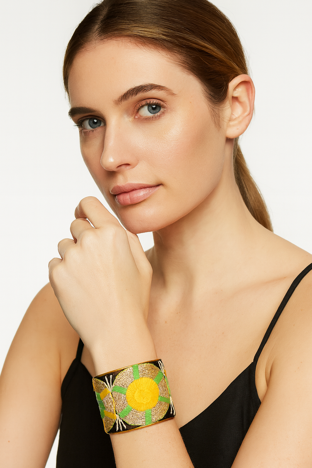 Model wearing the Redd Dott Micah 2-inch cuff bracelet, designed with vibrant yellow sunburst embroidery accented by green and metallic threads on a deep black base, framed in gold for a radiant finish.