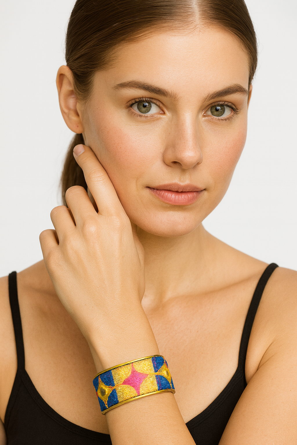 Model wearing the Redd Dott Mirin 1-inch cuff bracelet, featuring a bold starburst pattern in gold, pink, and blue embroidery, framed with a sleek gold edge for a vibrant pop of color.