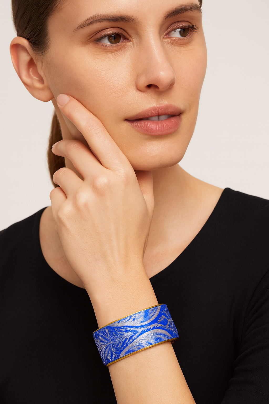 Model wearing the Redd Dott Myra 1-inch cuff bracelet, featuring a royal blue base with metallic silver leaf-inspired patterns, finished with a gold trim.