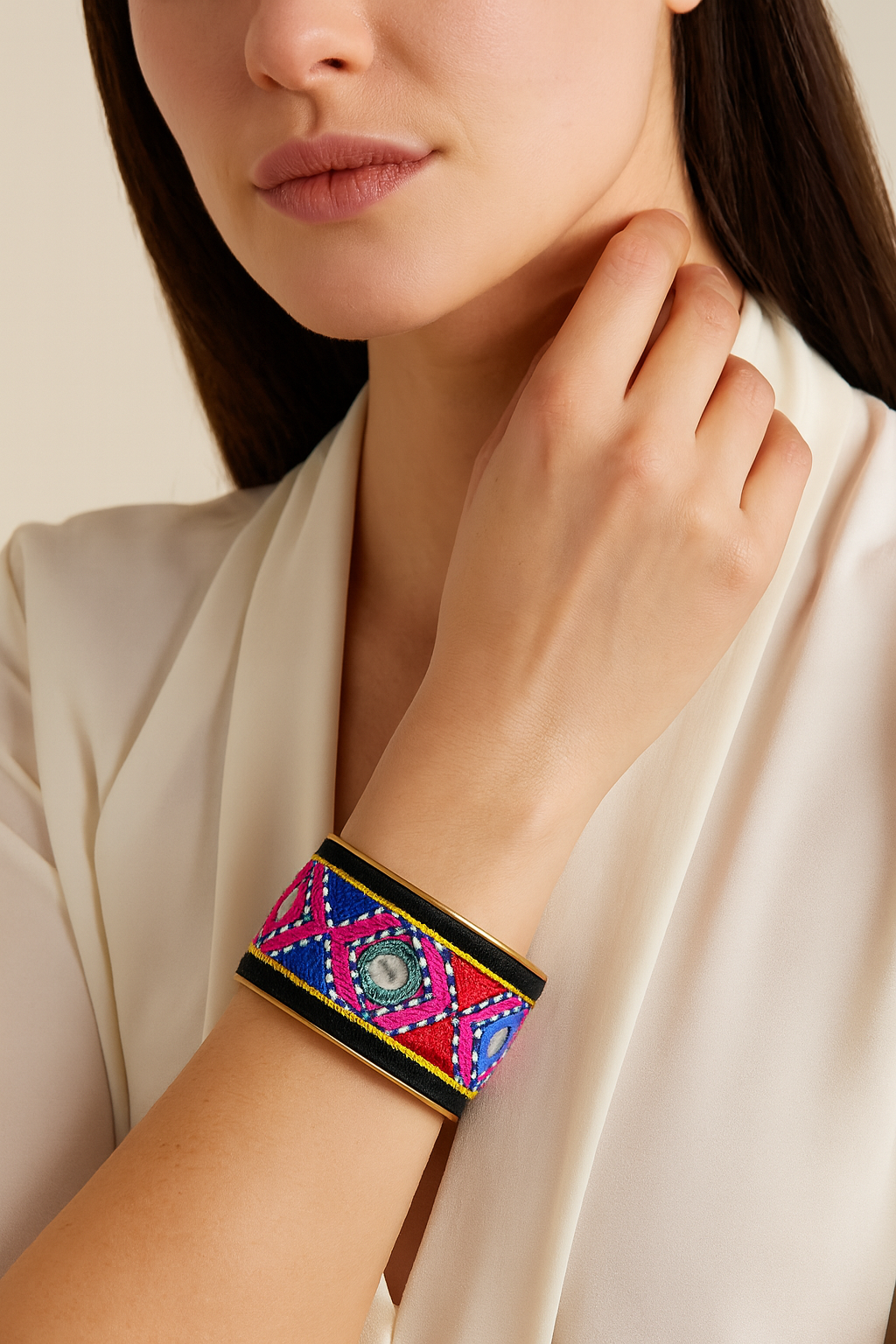 Model wearing the Redd Dott Nadia 1-inch cuff bracelet, featuring bold red, blue, pink, and yellow embroidered geometric patterns with circular mirrored accents, framed in gold.