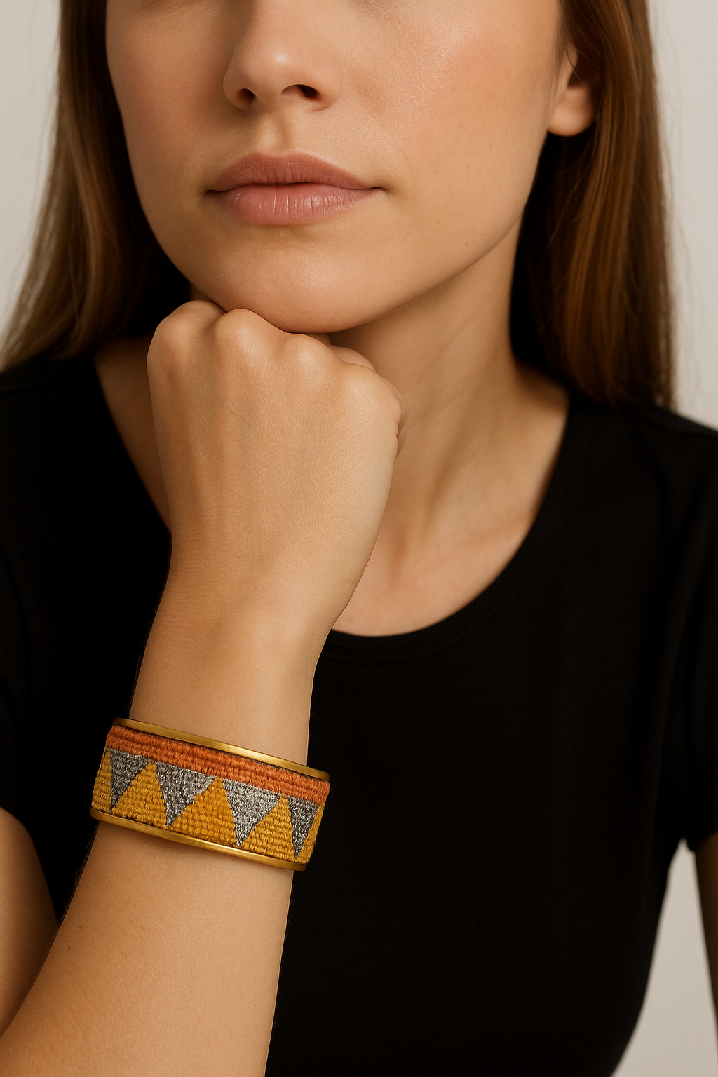Model wearing the Redd Dott Nadine 1-inch cuff bracelet, featuring hand-embroidered orange, yellow, and silver triangle motifs on a woven base, framed with gold edging.