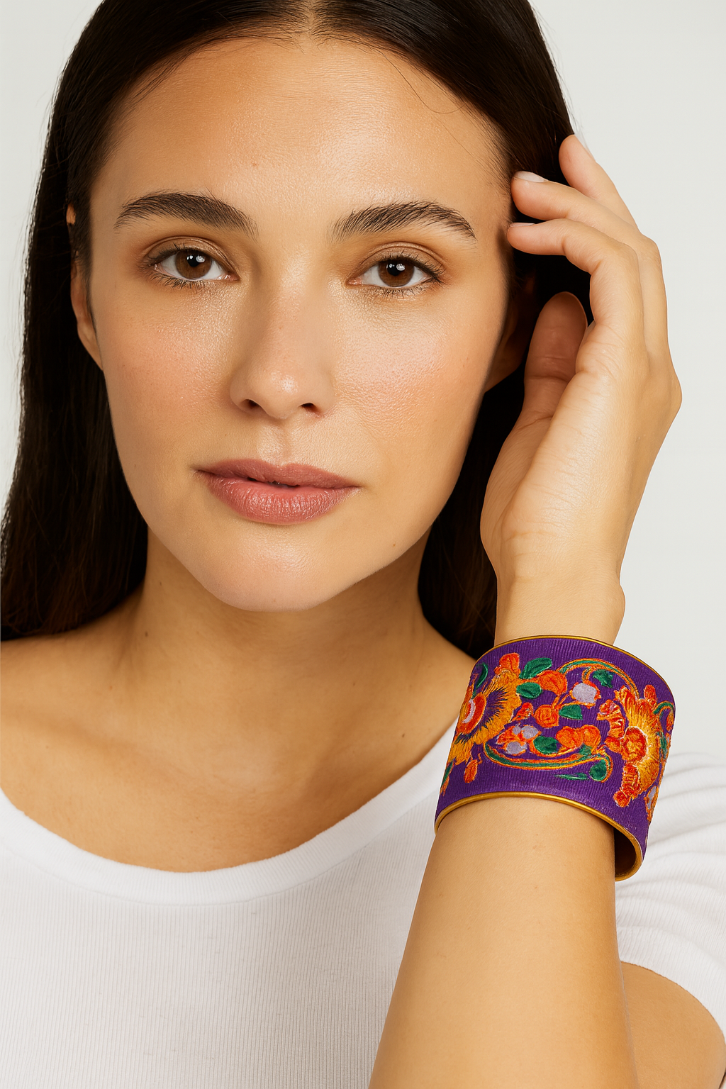 Model wearing the Redd Dott Nakia 3-inch cuff bracelet, designed with bold orange floral embroidery on a deep purple base, framed in gold for a vibrant statement look.