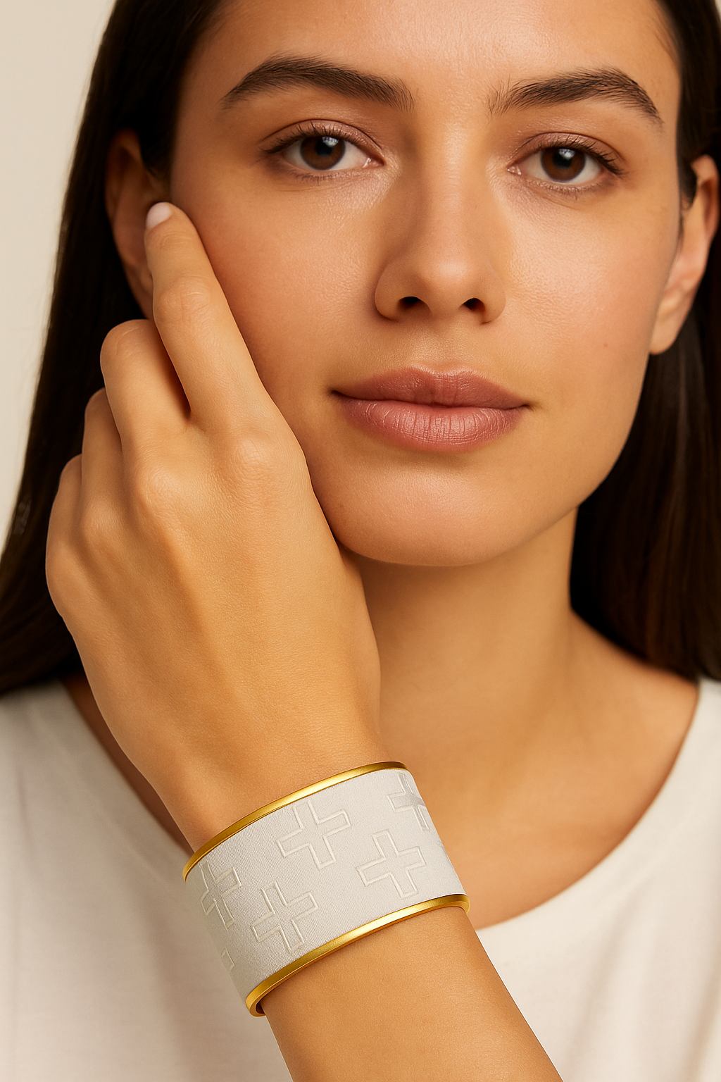 Model wearing the Redd Dott Naveah 2-inch cuff bracelet, featuring a sleek white base embossed with minimalist cross patterns, framed in polished gold for a bold yet modern statement.