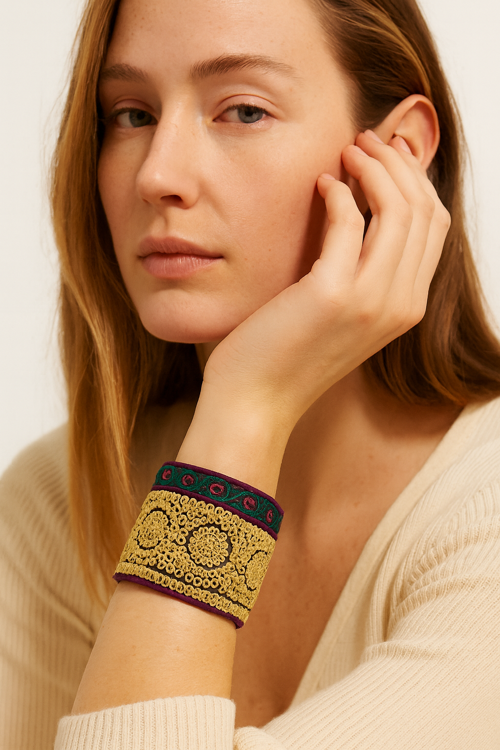 Model wearing the Redd Dott Niccola 3-inch cuff bracelet, featuring ornate golden embroidery with intricate circular motifs, bordered by deep green and burgundy accents for a rich, regal finish.