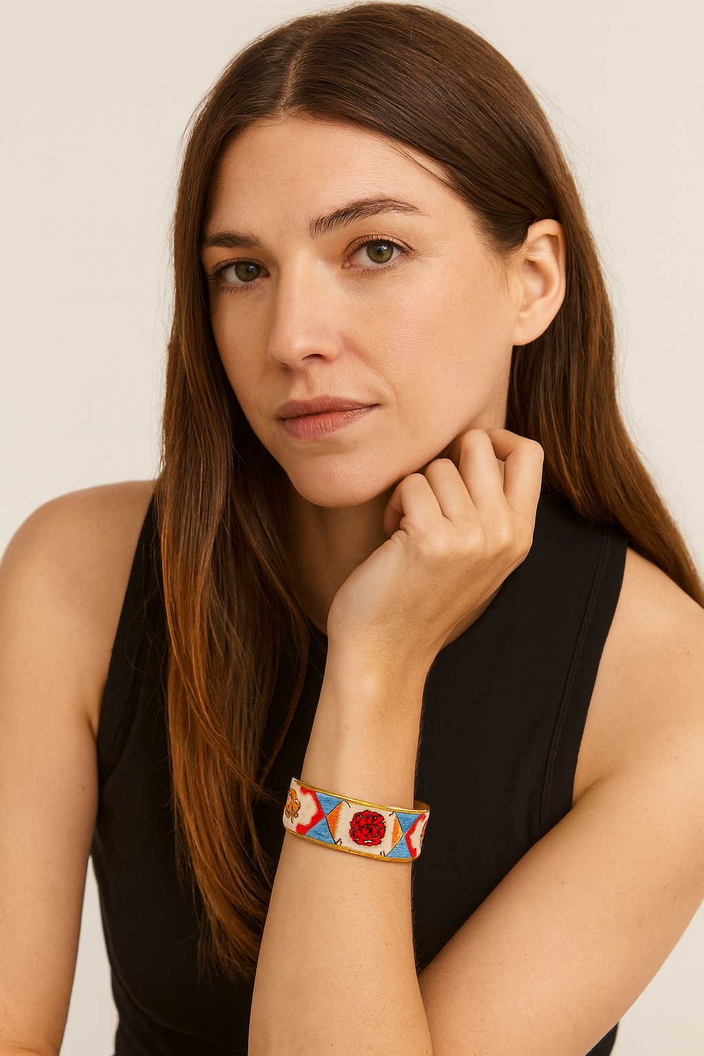 Model wearing the Redd Dott Nola 1-inch cuff bracelet, featuring bold geometric blue and white triangles accented with vibrant red floral embroidery, framed with a metallic gold edge.