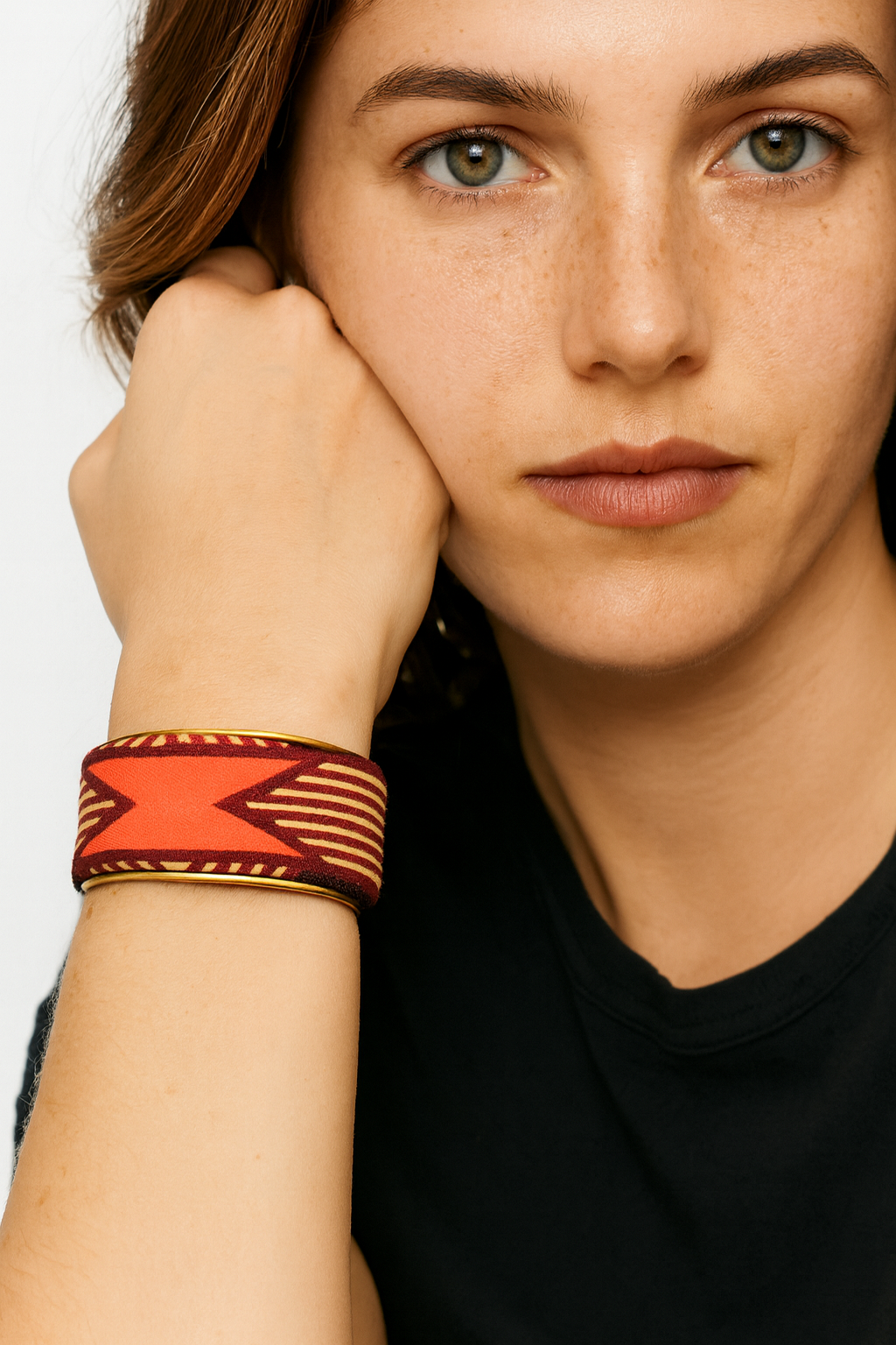 Model wearing the Redd Dott Nyx 1-inch cuff bracelet, featuring bold geometric tribal-inspired patterns in deep red, gold, and orange tones, outlined with a sleek metallic trim.