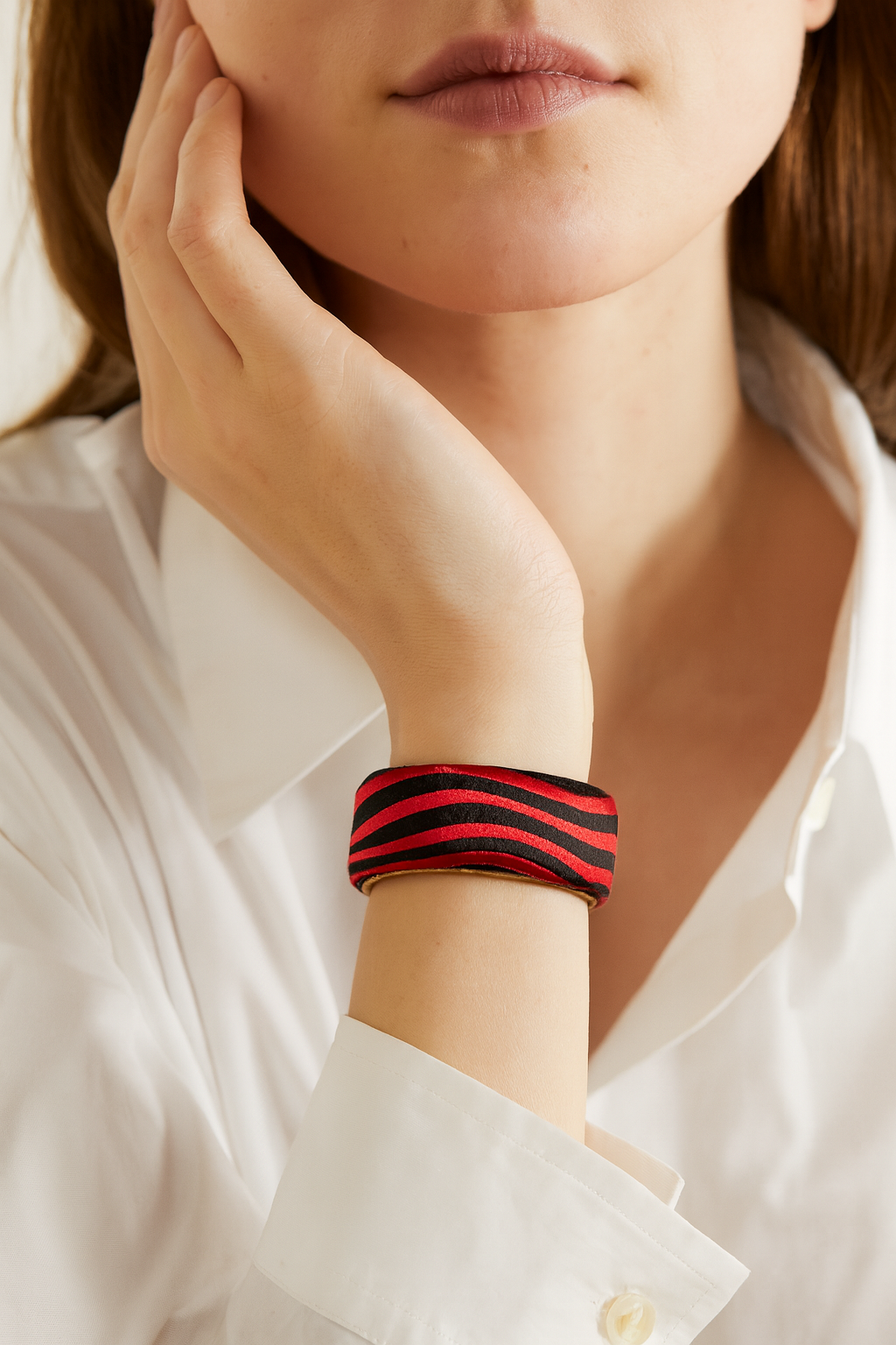 Model wearing the Redd Dott Odessa 1-inch cuff bracelet, crafted in smooth satin with bold red and black diagonal stripes, a sleek and striking accessory for modern styling.