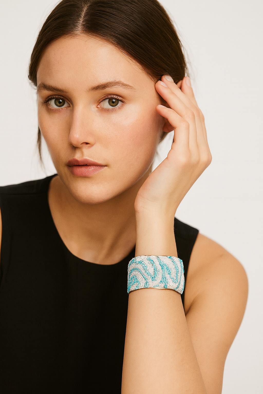 Model wearing the Redd Dott Odette 2-inch cuff bracelet, intricately beaded in shimmering aqua and silver tones with swirling patterns, creating a fresh and elegant statement piece.