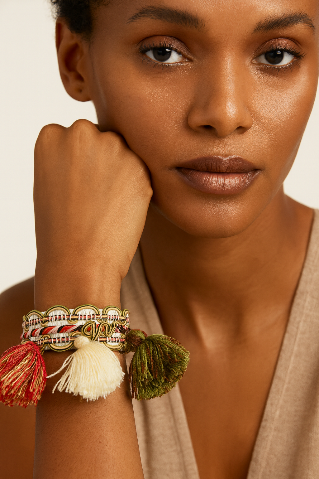 Model wearing the Redd Dott Olive 1-inch cuff bracelet featuring intricate woven detailing in green, cream, and red, accented with large statement tassels in olive green, ivory, and crimson for a playful yet bold bohemian look.