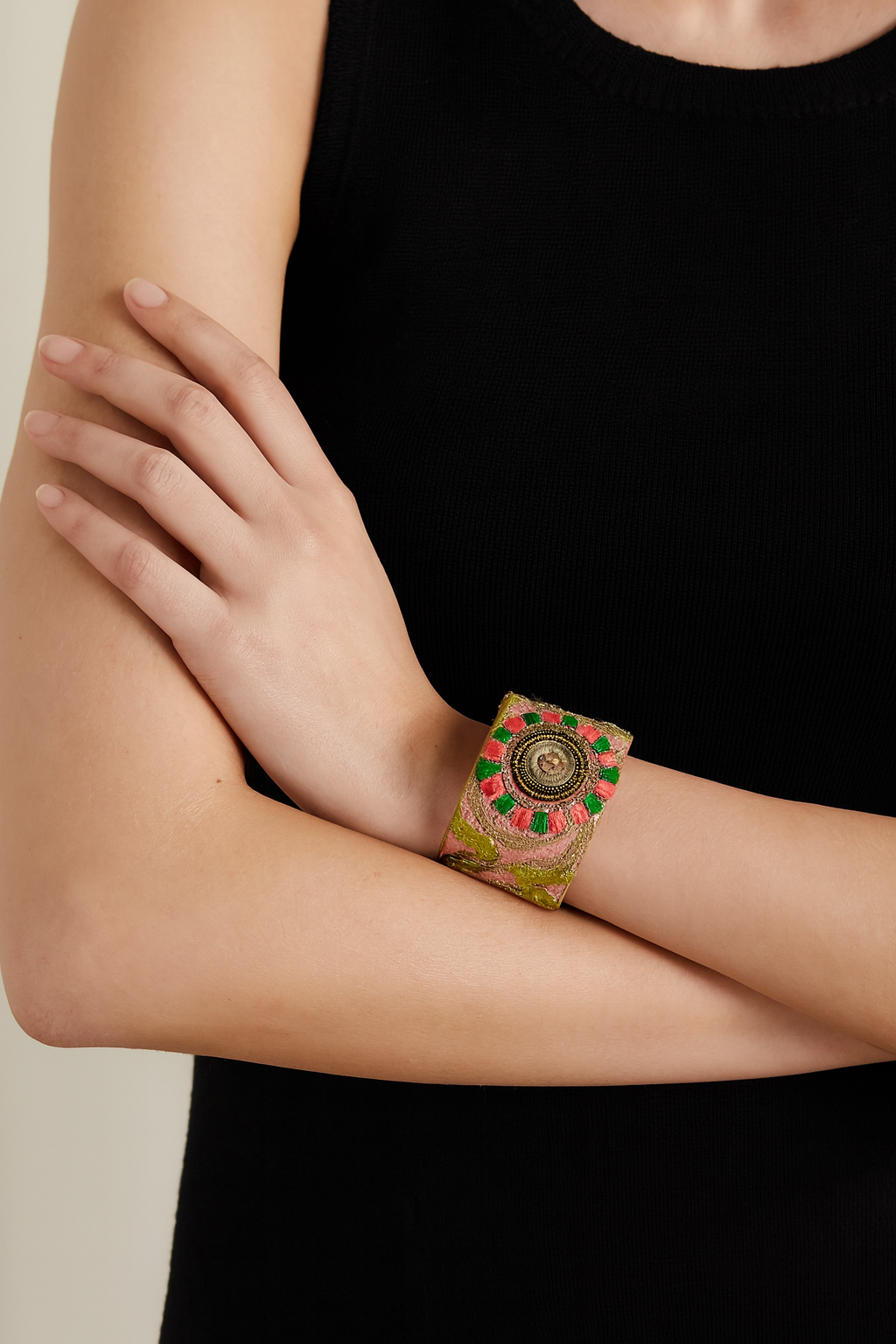 Model wearing the Redd Dott Ophelia 2-inch cuff bracelet featuring a bold embroidered design in pink, green, and gold with an ornate circular medallion centerpiece, creating a striking statement accessory against a black sleeveless top.