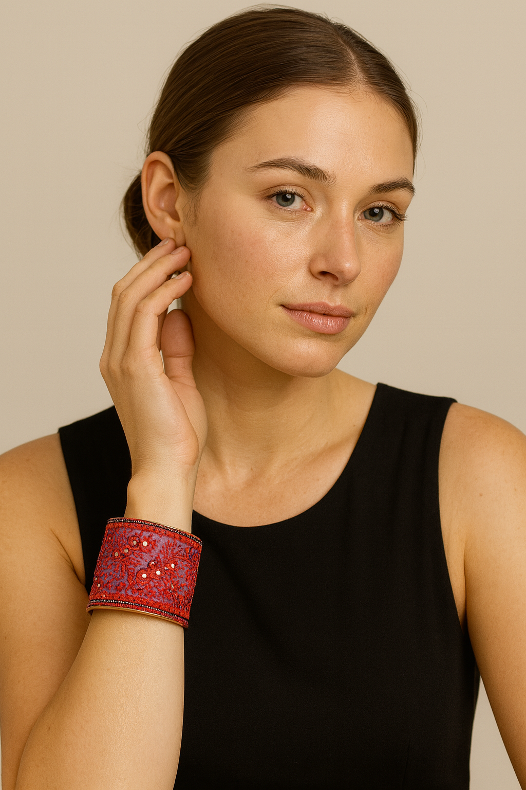 Model wearing the Redd Dott Orion 3-inch cuff bracelet in vibrant red with intricate embroidered patterns and bead accents, creating a bold statement piece against a classic black dress.