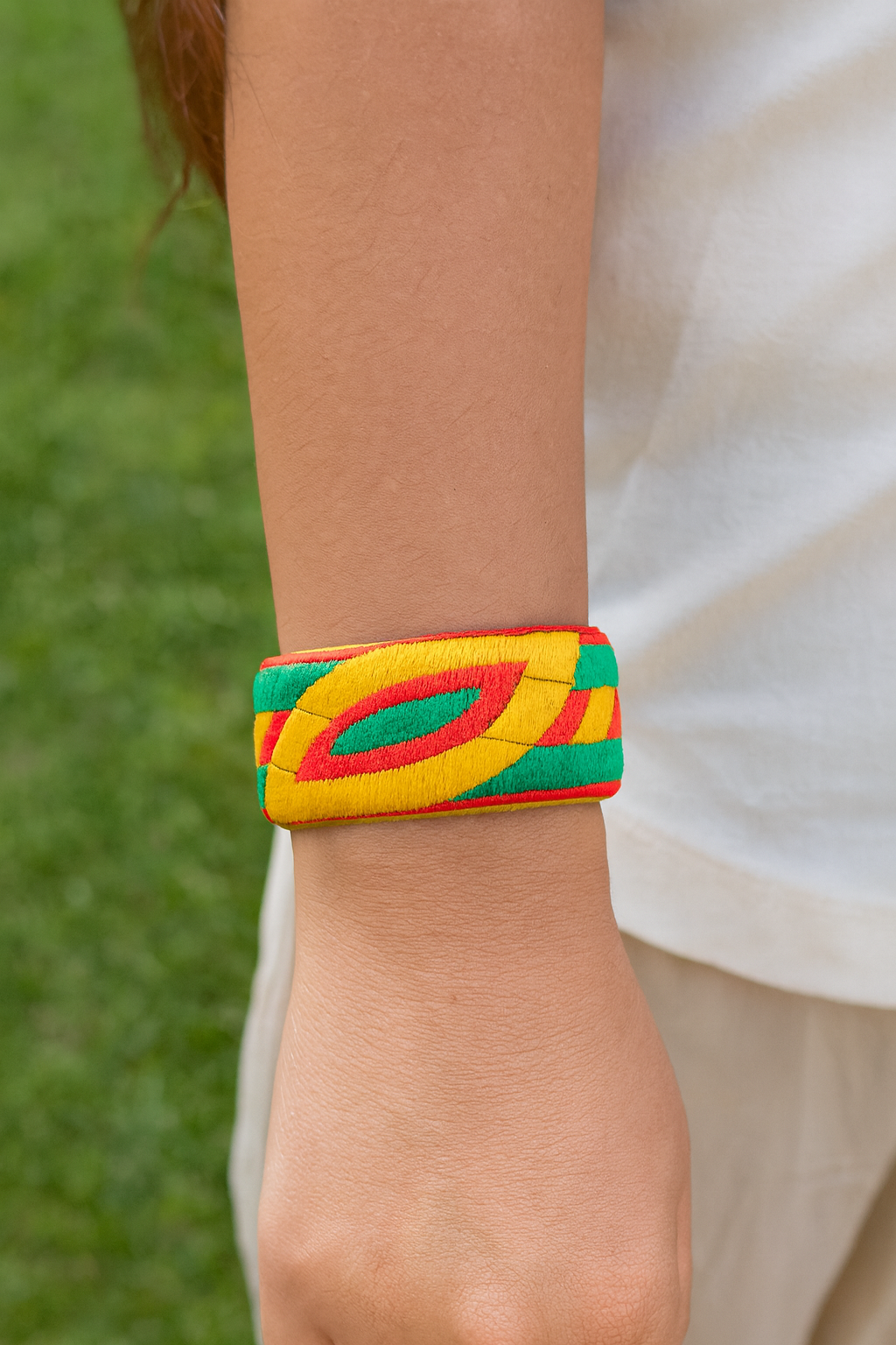 Close-up of the Redd Dott Orla 1-inch cuff bracelet featuring bold embroidered patterns in bright yellow, green, and red, creating a vibrant and eye-catching geometric design.