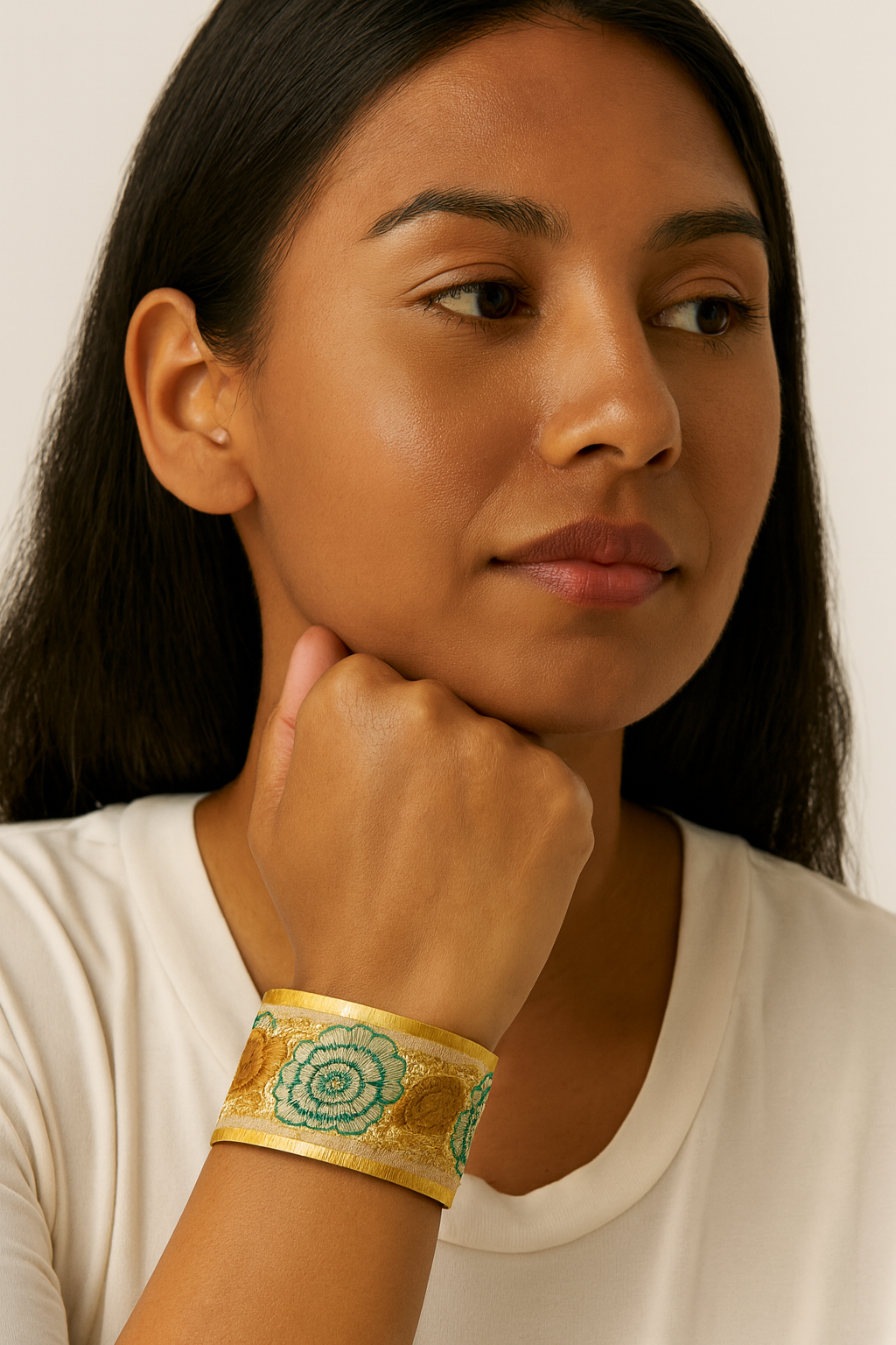 Woman wearing the Redd Dott Perry 2-inch cuff bracelet, designed with golden fabric and embroidered green floral medallions framed in gold.