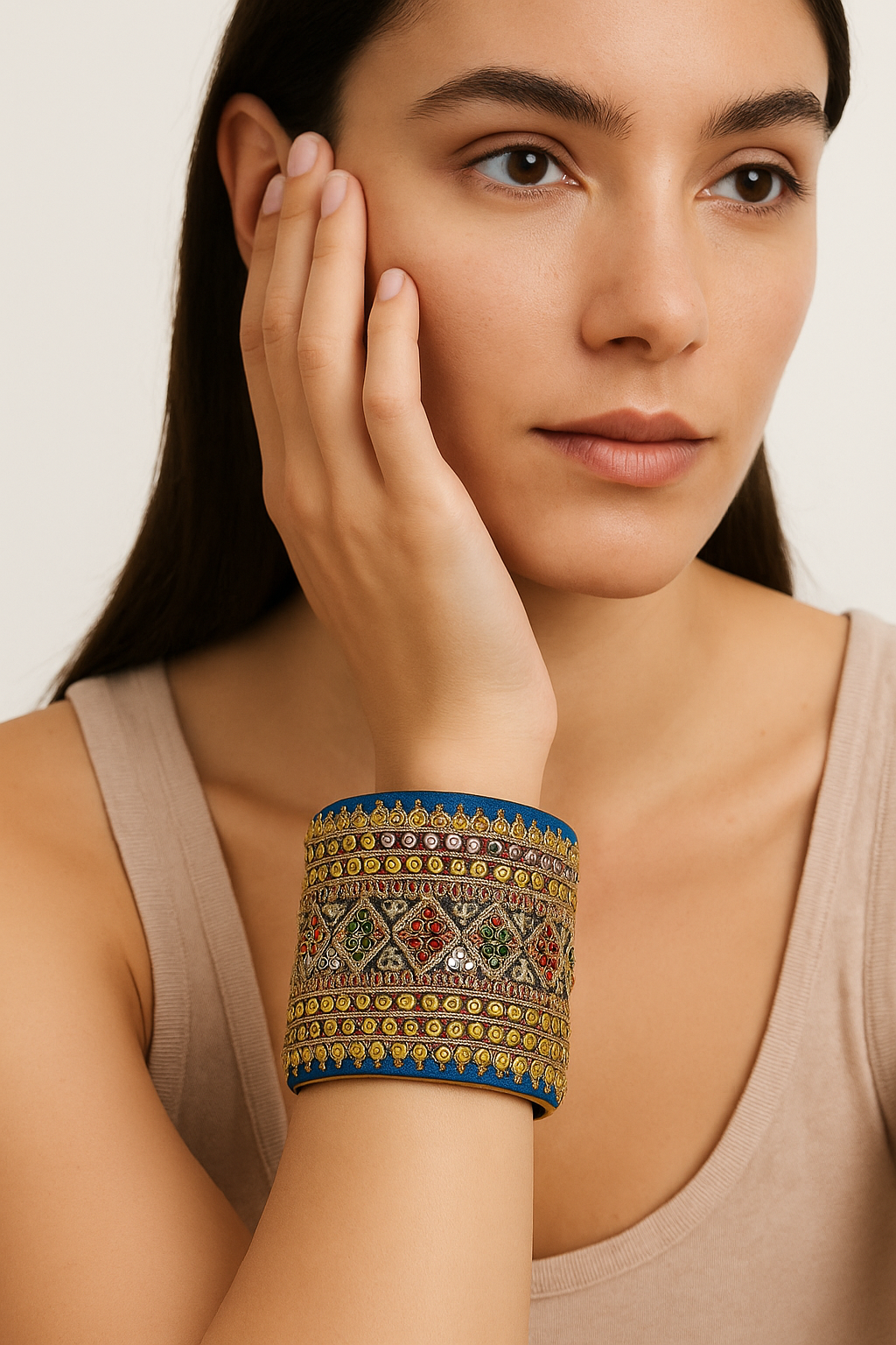 Close-up of a woman wearing the Redd Dott Pipit 3-inch gold cuff bracelet, featuring royal blue fabric with ornate multicolor embroidery, jeweled diamond patterns, and intricate gold detailing.