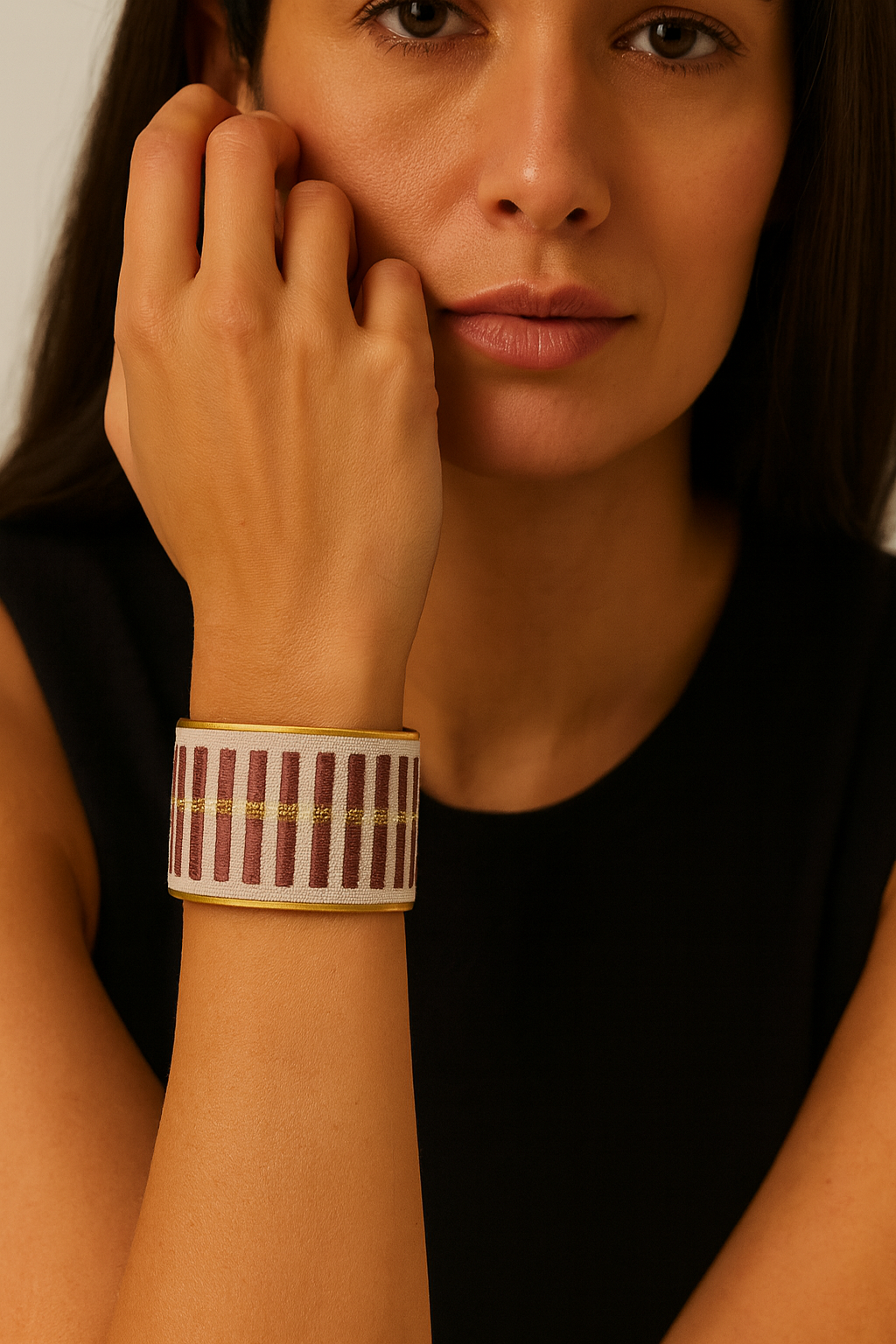 Close-up of a woman wearing the Redd Dott Plum 2-inch gold cuff bracelet, featuring a cream fabric base with vertical plum-colored embroidery and delicate gold accents.