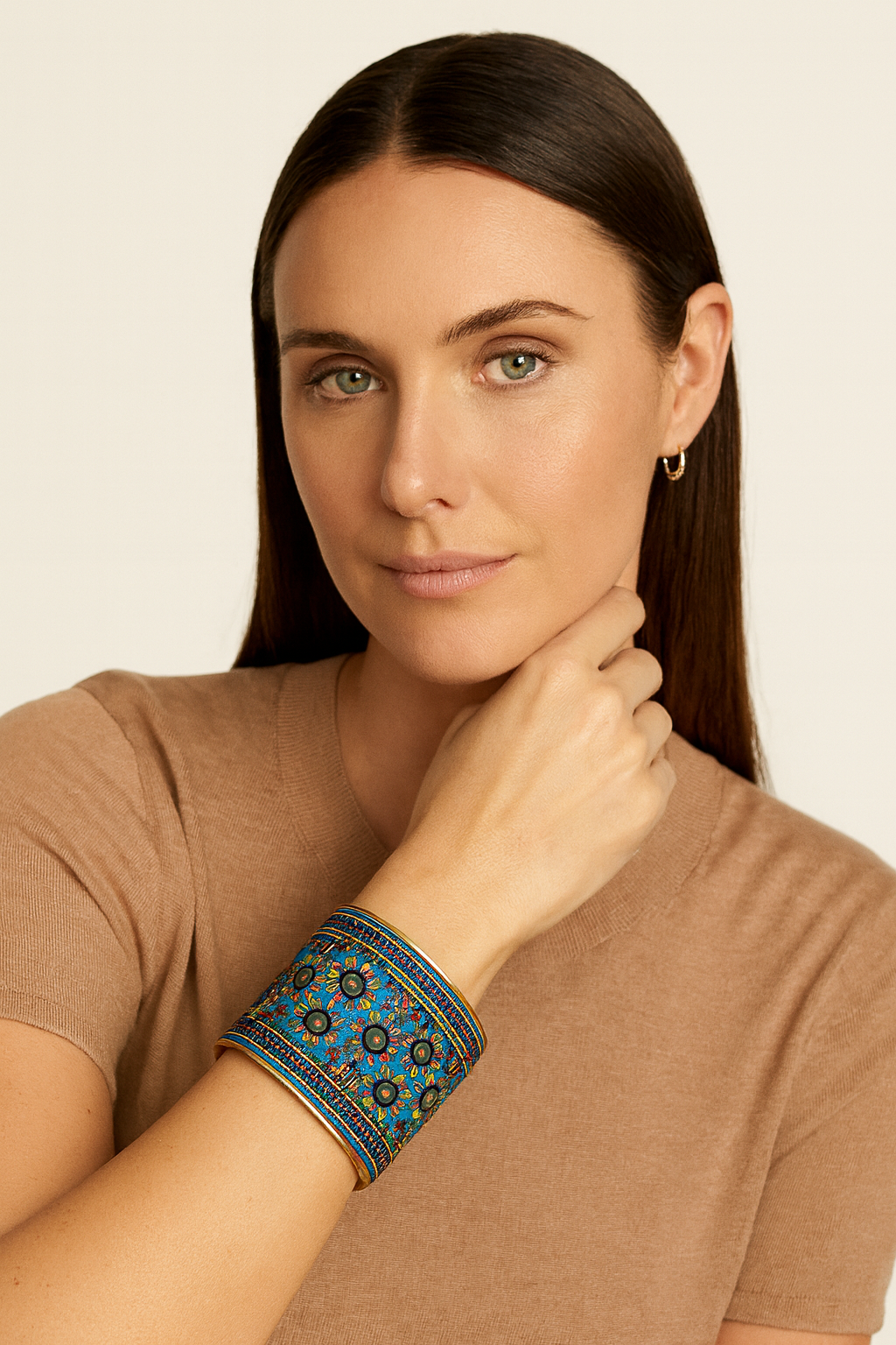 Close-up of a woman wearing the Redd Dott Raven 3-inch gold cuff bracelet, featuring turquoise fabric with intricate floral embroidery in green, red, and gold accents.