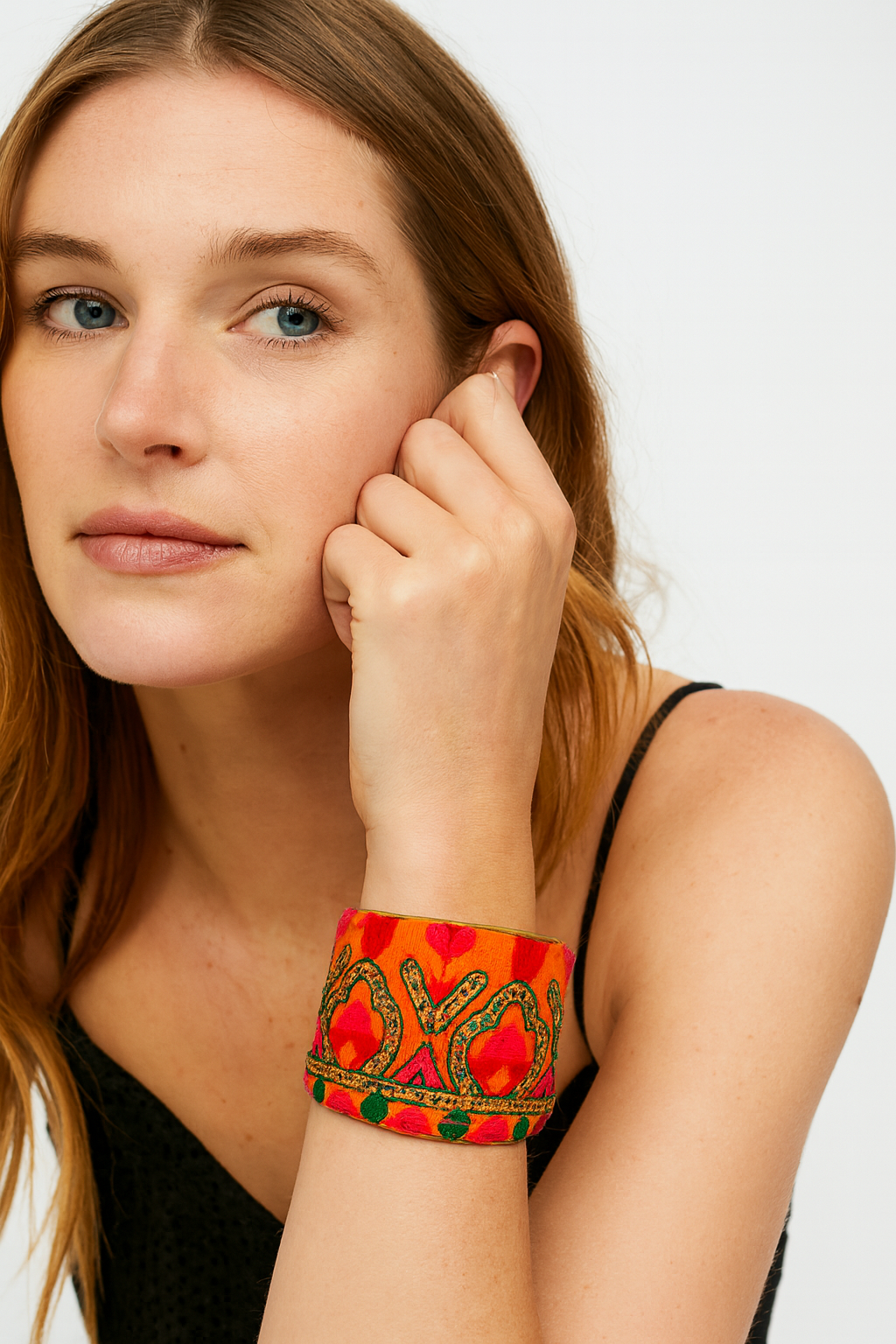 Close-up of the Redd Dott Rebekah 2-inch gold cuff bracelet, featuring vibrant orange fabric with bold pink and red embroidery, green accents, and gold sequin detailing.