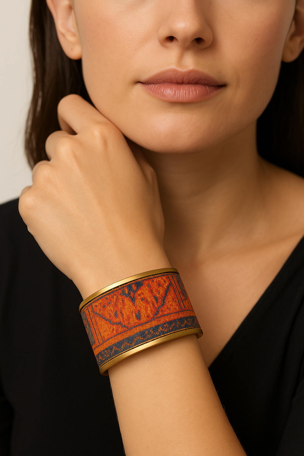 Close-up of a woman wearing the Redd Dott “Rusty” 2″ cuff—burnt-orange textile bracelet with a navy, rug-inspired border and brass edging.