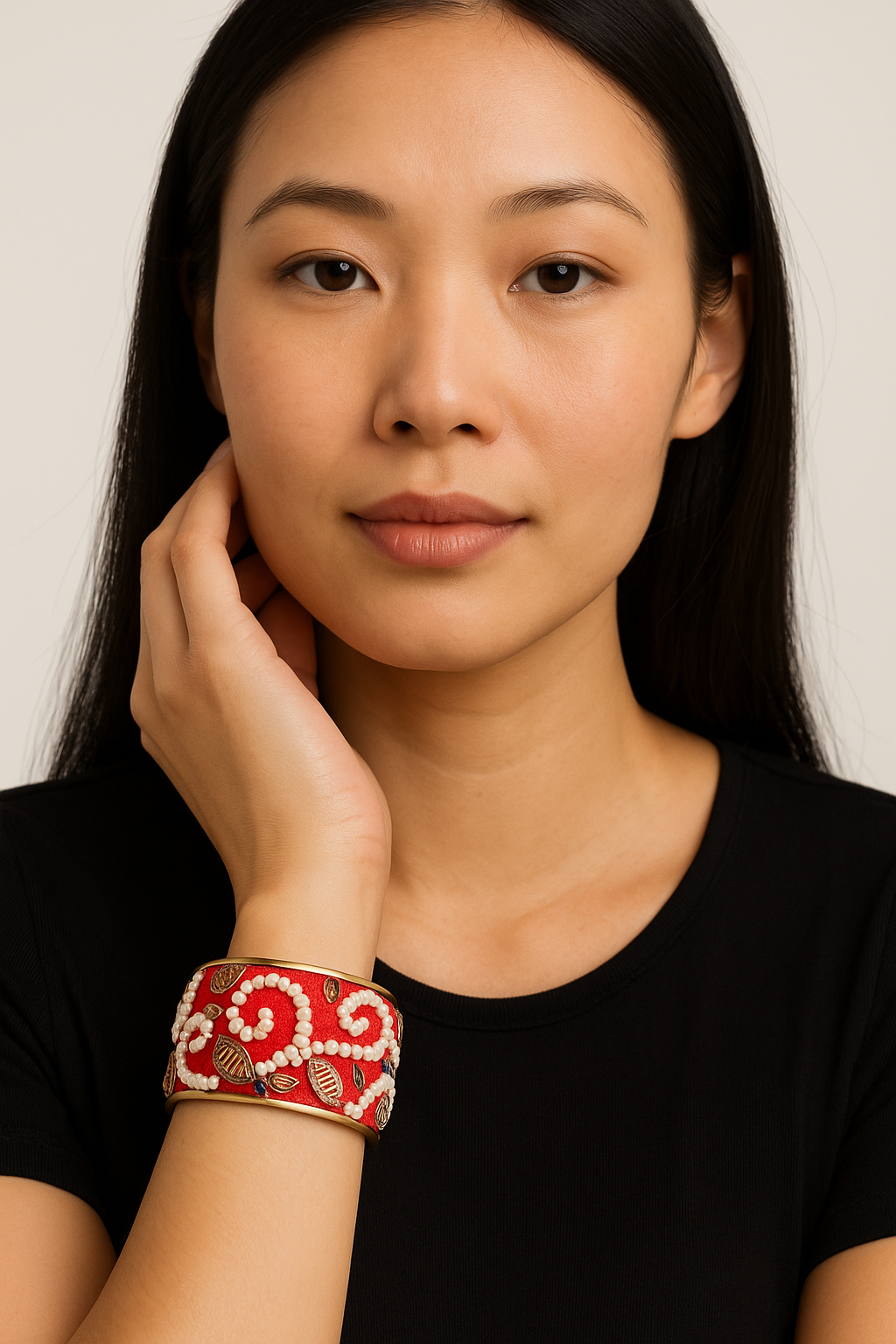 Close-up of a woman in a black tee wearing the Redd Dott “Selena” 1″ cuff—cherry-red textile base with white seed-bead scrolls, small blue/coral bead accents, gold leaf appliqués, and matte-brass edges.