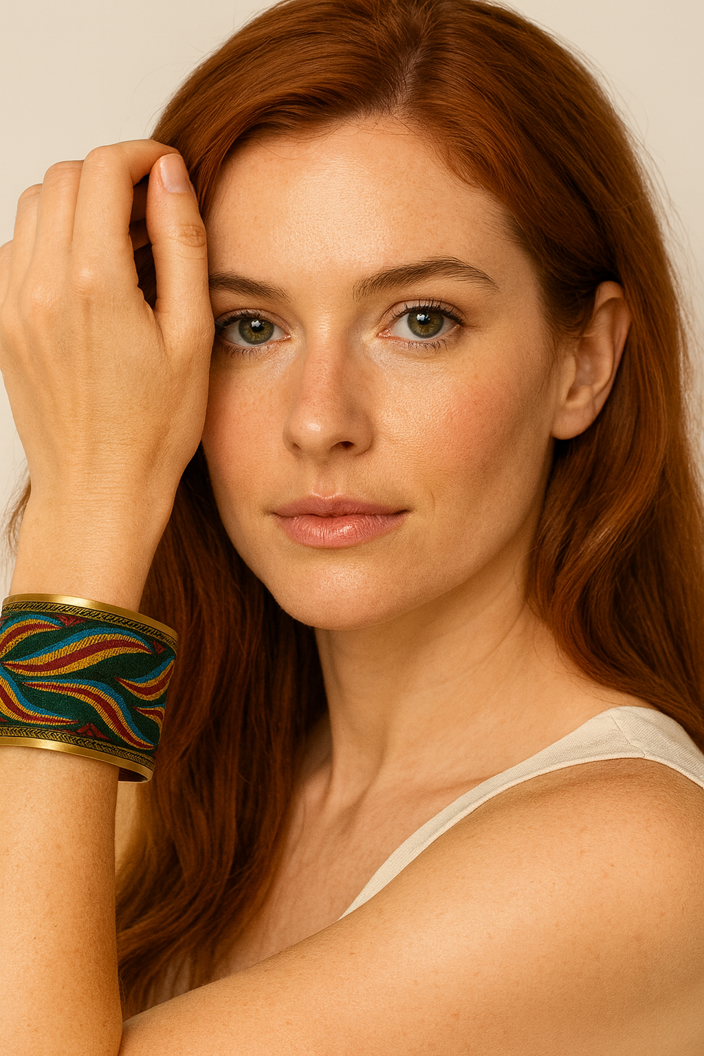 Close-up of a woman wearing the Redd Dott “Shadi” 2″ cuff—deep forest-green textile with flowing wave embroidery in saffron, rust, teal and gold, finished with etched antique-brass borders and an open back.