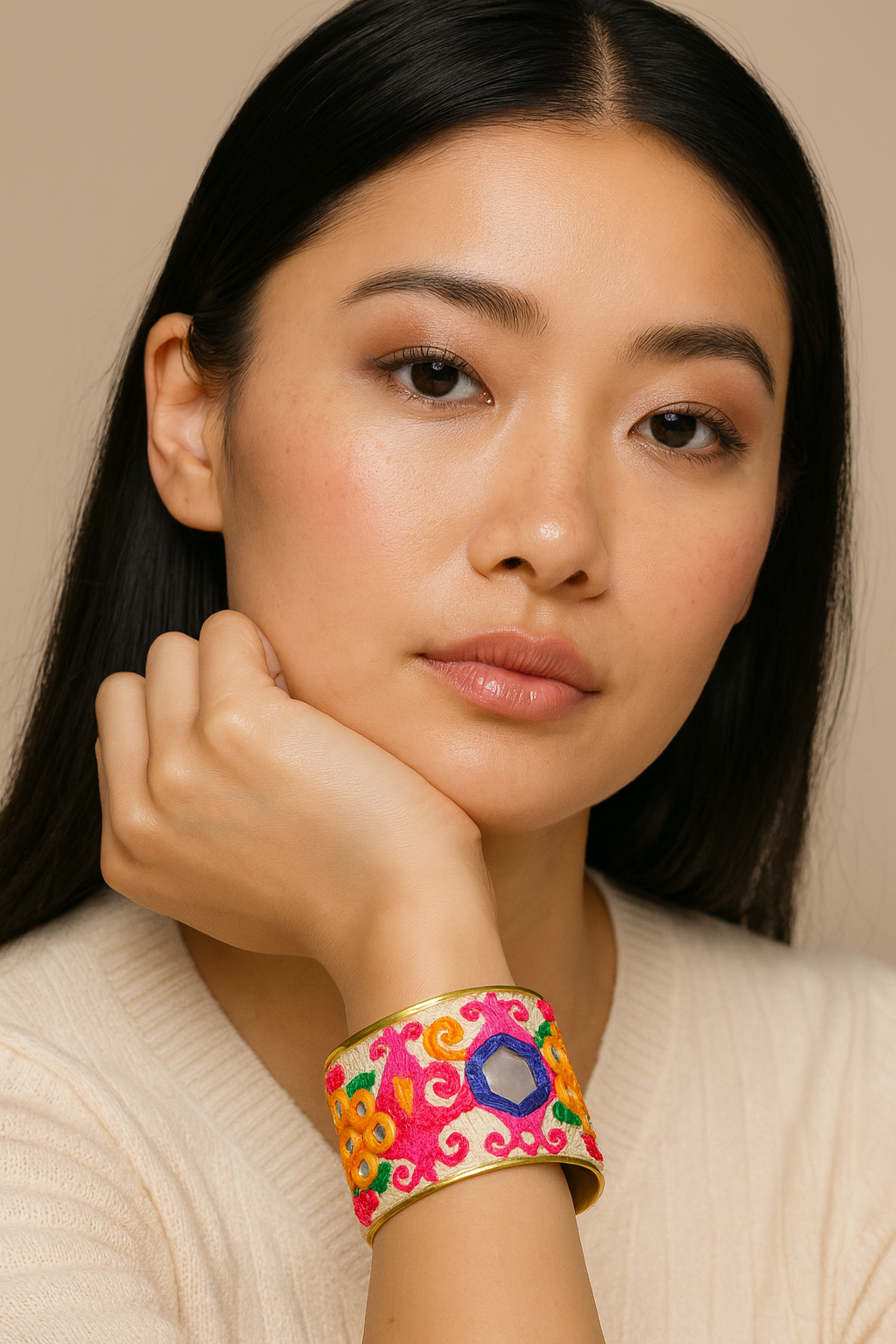 Close-up of a woman’s wrist wearing the Redd Dott “Silvermist” 2″ statement cuff—vivid fuchsia ground with hot-pink scroll embroidery, saffron rosette motifs, emerald leaves, and a cobalt-bordered mirror accent—finished with polished brass edges and an open back.