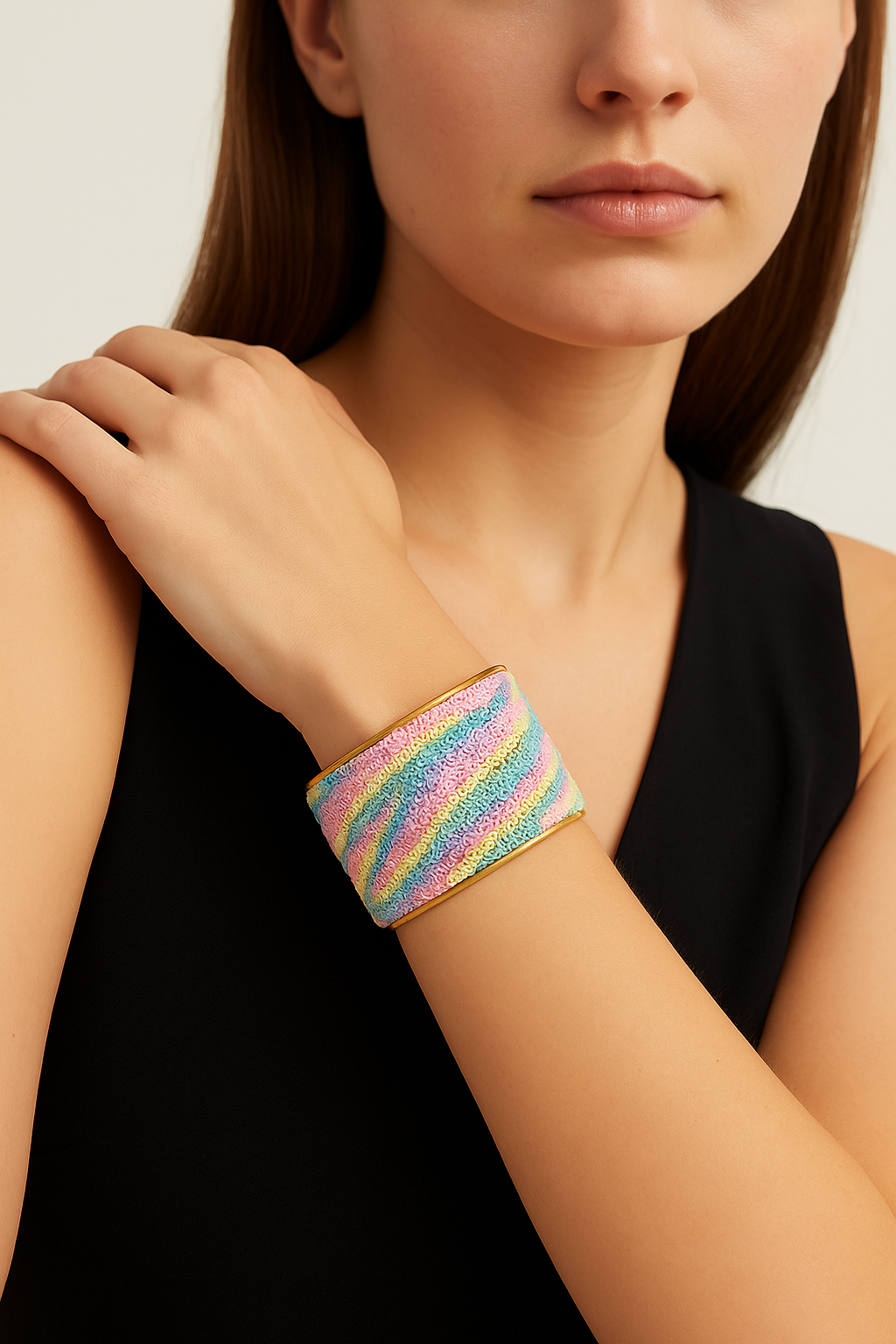 Close-up of a woman’s wrist and lower face, wearing the Redd Dott “Zoey” 2″ wide sequin cuff. The bracelet’s fine mesh base is densely stitched with tiny pastel-hued sequins in undulating stripes of mint, blush pink, lavender, and lemon, each catching the light against the warm brass open-back frame as her hand softly brushes her cheek.